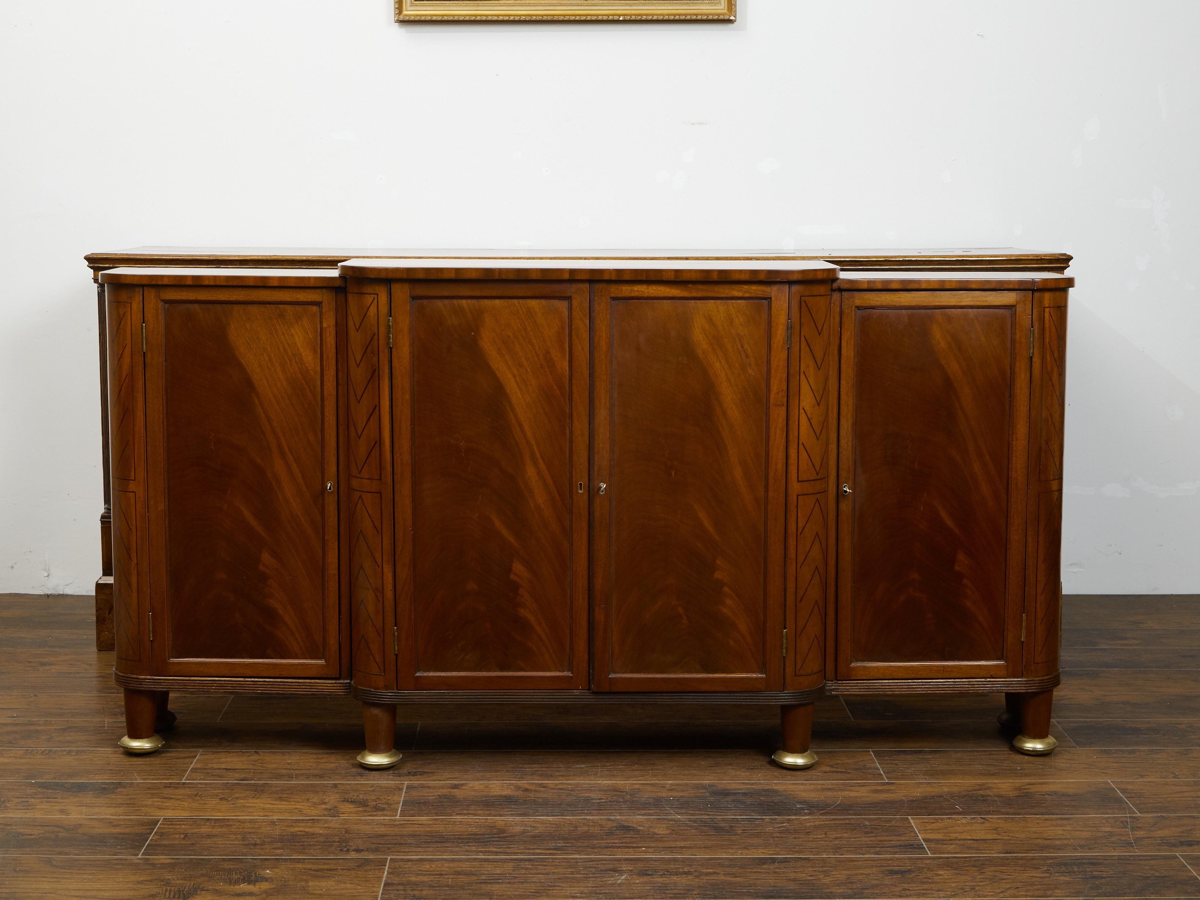 An English Regency period mahogany breakfront buffet from the early 19th century, with four doors, geometric inlay and brass details. Created in England during the Regency period in the second quarter of the 19th century, this mahogany buffet