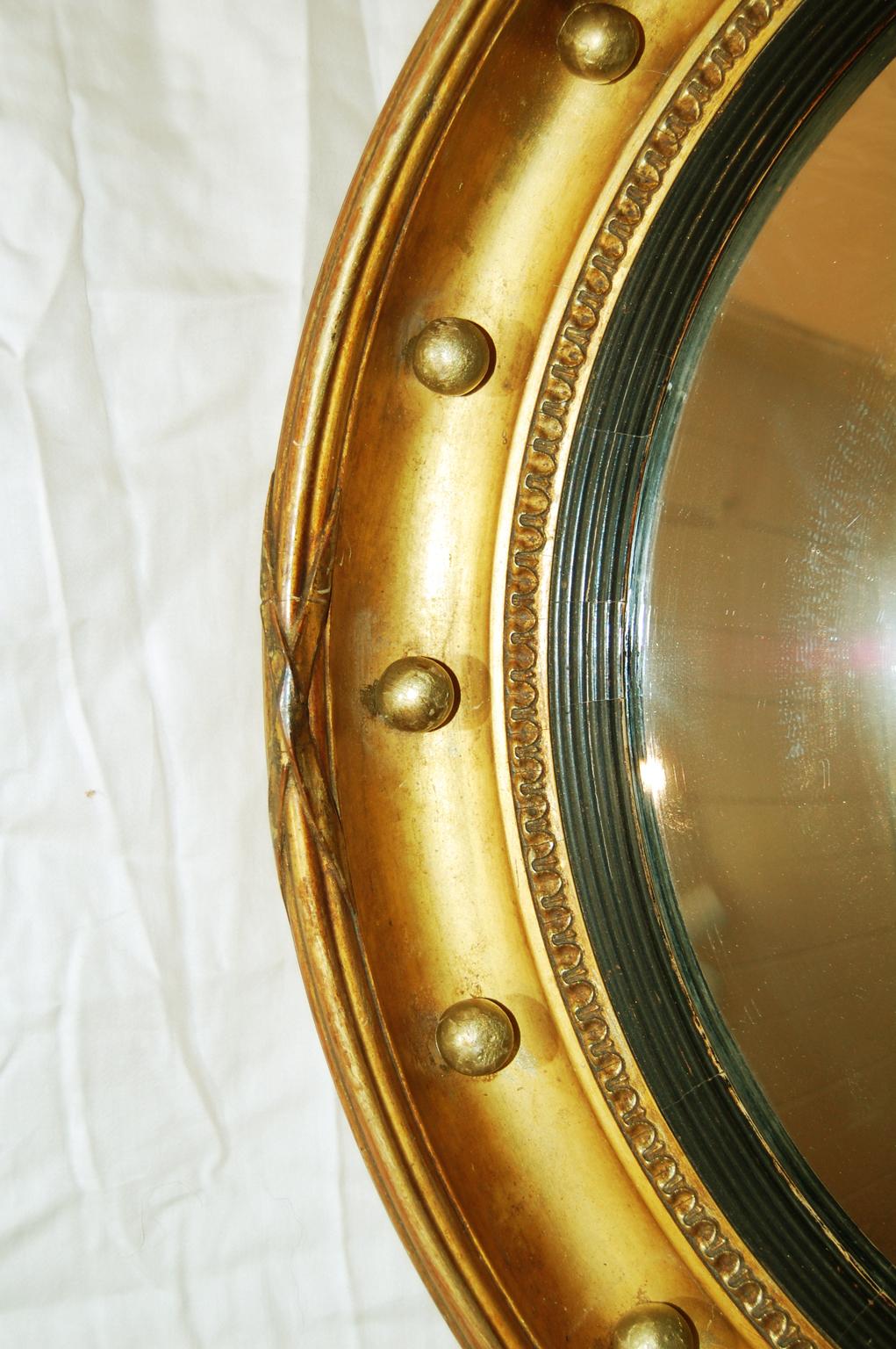 English Regency Style Giltwood convex mirror with black reeded liner, carved, gesso and gilded frame, and gold balls in the deep cove of the frame. The carved reeded edge of the mirror is echoed in the black liner, circa 1850.