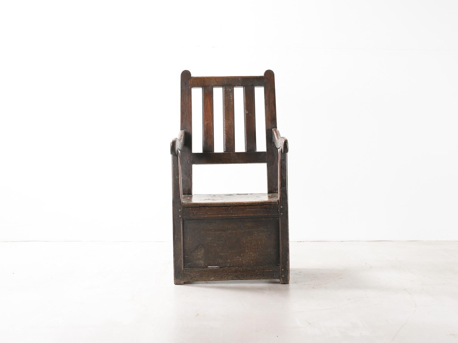 Sillón de madera oscura de la época de la Regencia con espacio de almacenamiento bajo el asiento. Bonita pátina en toda la superficie. 