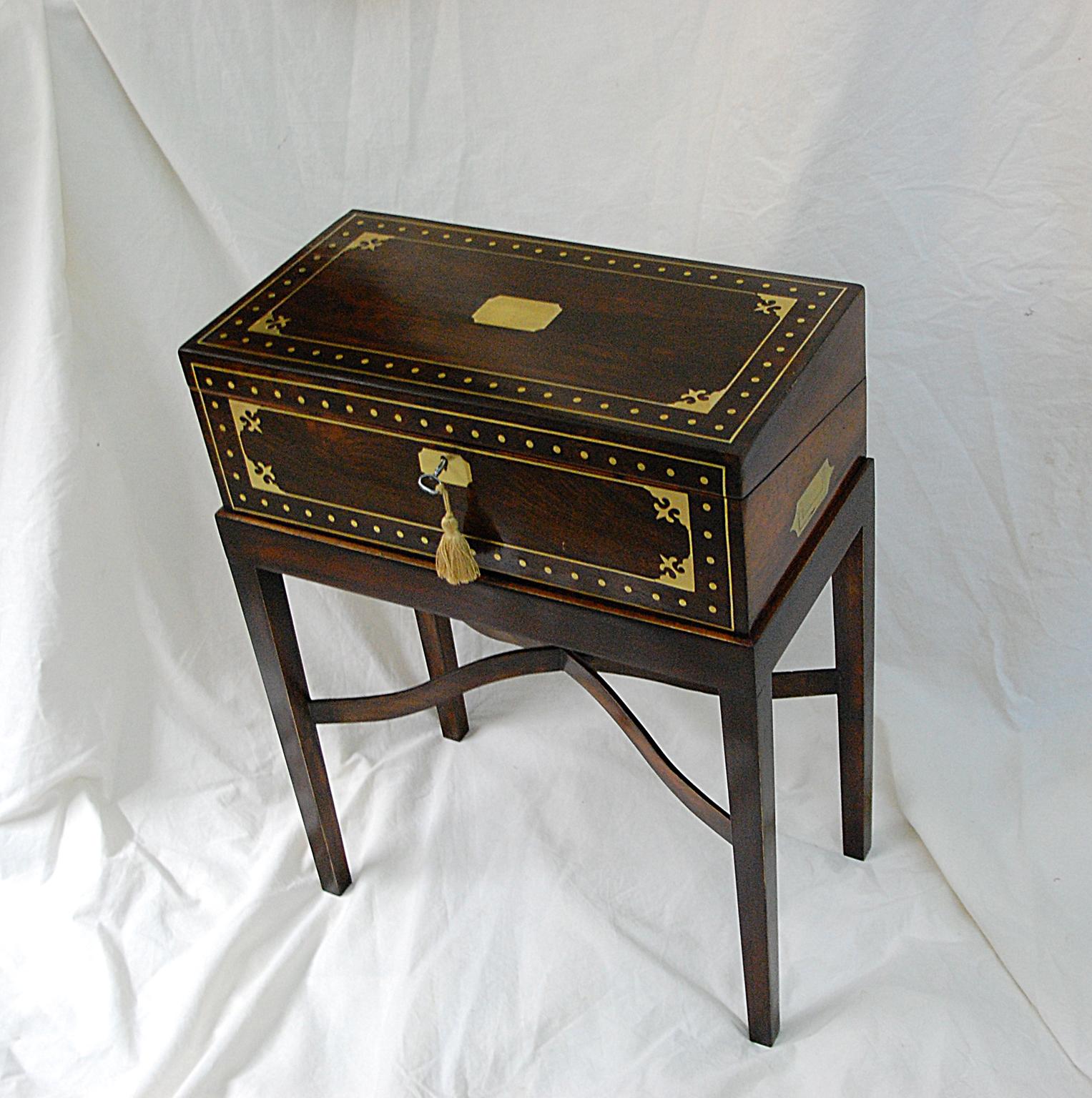 English Regency period rosewood writing box, elaborately inlaid with brass, now on a custom made stand with arched cross stretcher. The interior of the writing box has a sloping tooled leather writing surface, covered pencil/pen holder, inkwell, and
