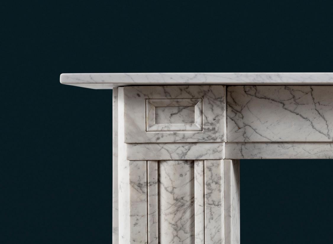 An antique Regency Carrara Marble fireplace surround with square corner blocks, the cushion moulded jambs with quarter-round returns, all in strongly figured marble.

A model exhibiting the Regency preference for a shallower frieze and shelf than
