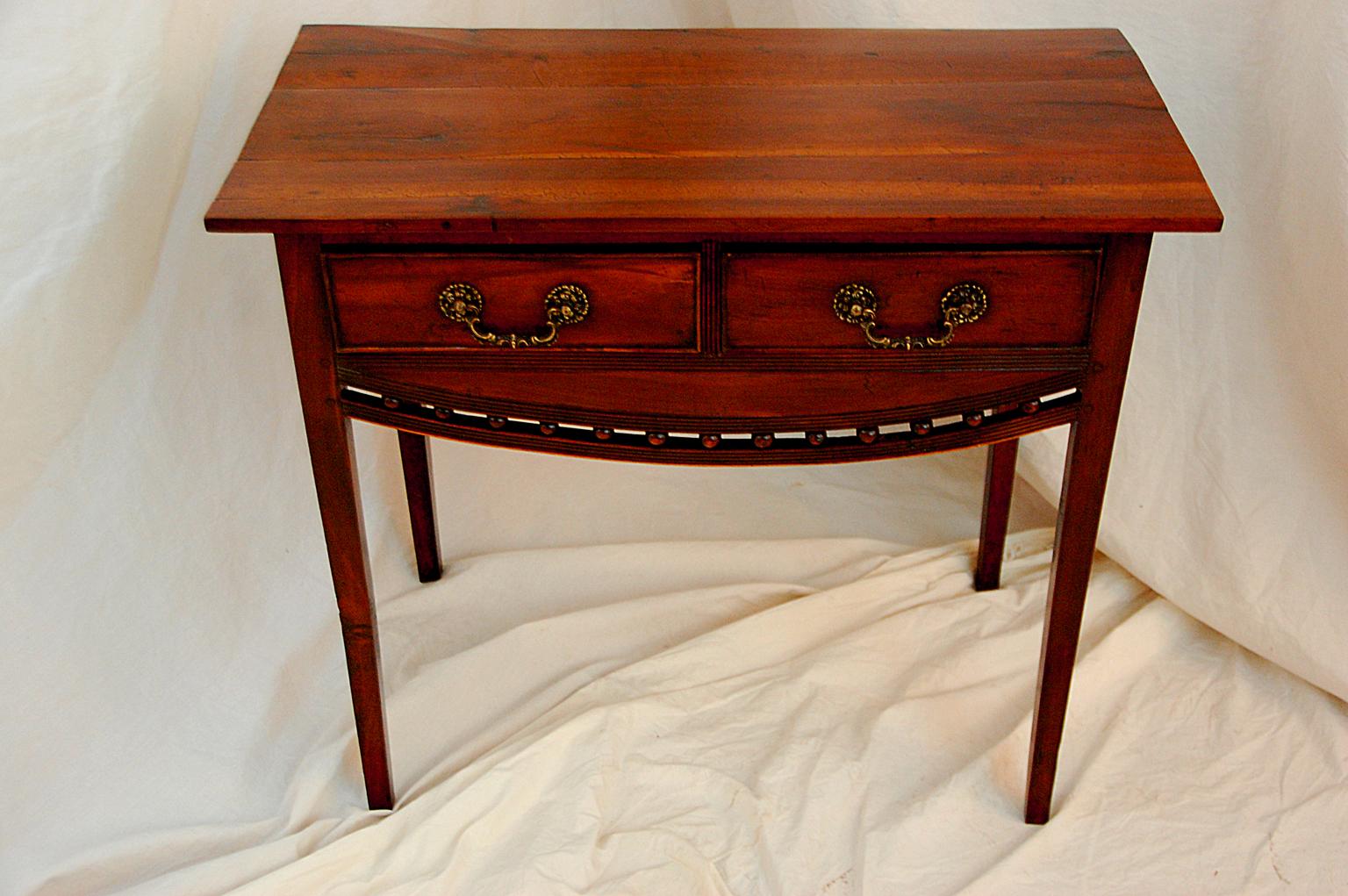 English Regency period fruitwood dressing table with two drawers, tapered legs and convex skirt. This table comes from the East Anglia area of England, one of the hall marks of these area is the convex reeded skirting with balls. This particular