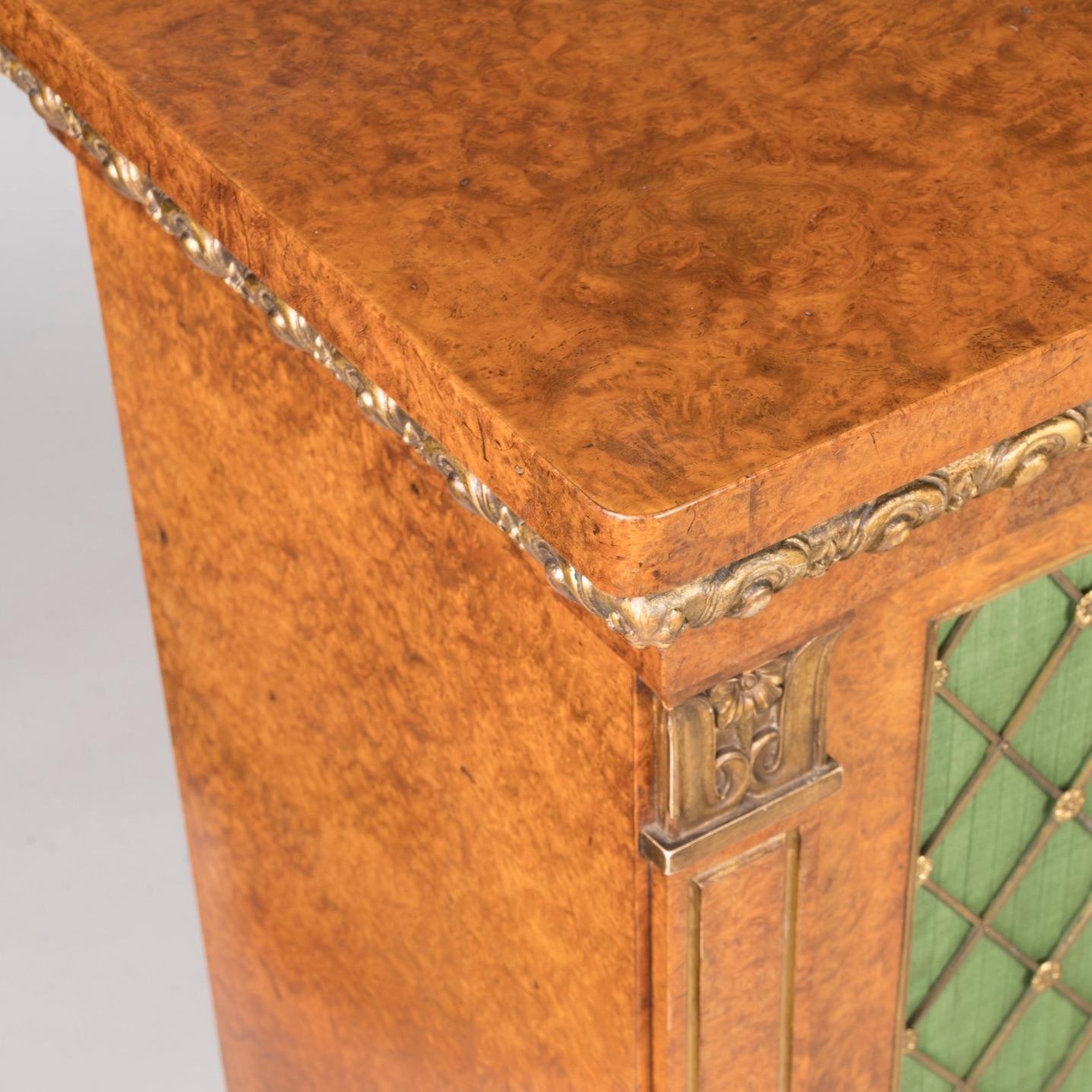 A regency period parcel gilt and Amboyna 
Breakfront side cabinet

Using the most striking amboyna veneers, of breakfront form and with parcel gilt highlights; the side cabinet resting on a plinth base, with three lockable doors having pleated