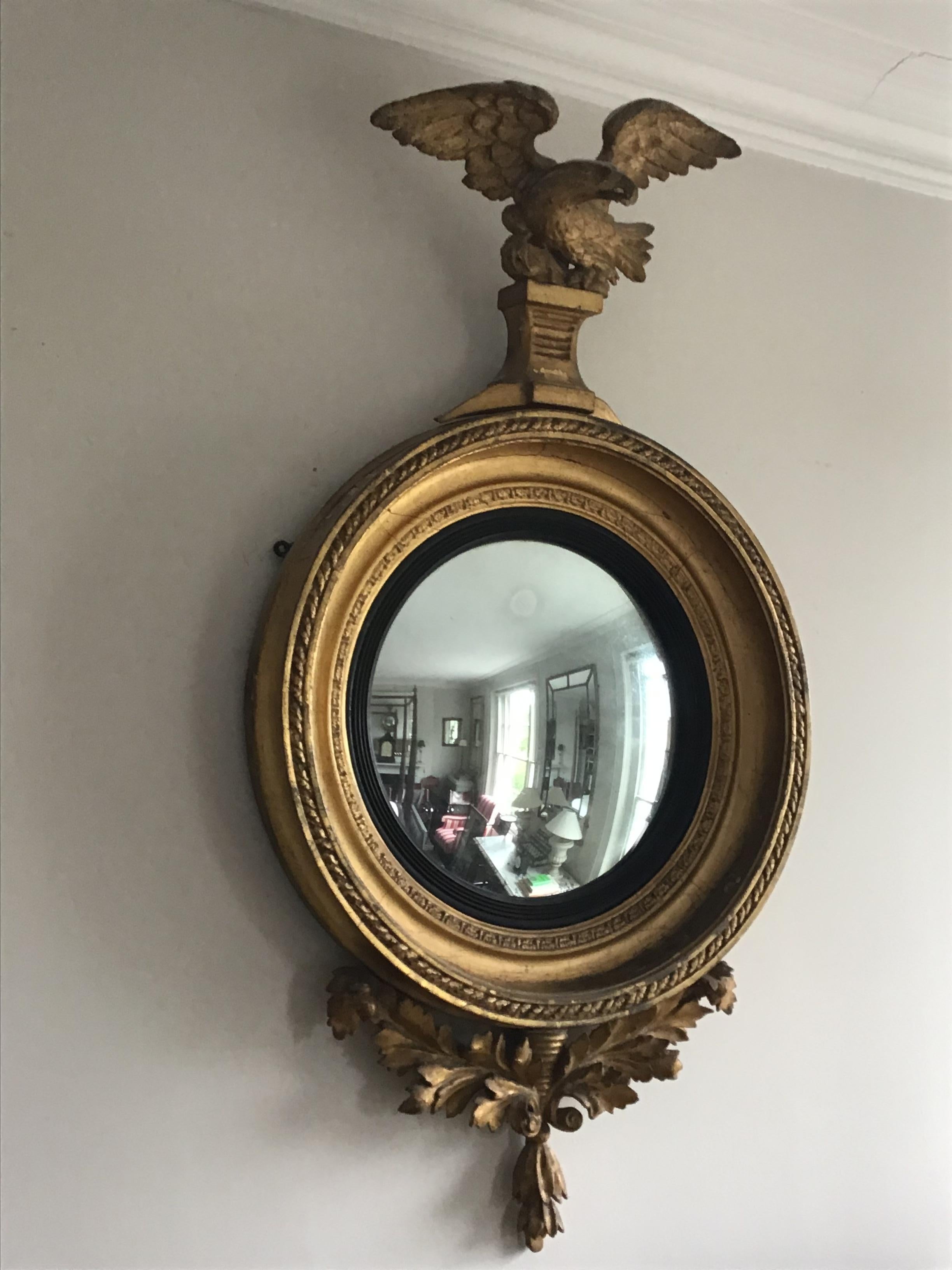 English Regency giltwood with carved spreading winged Eagle channelled foliate frame, convex plate and carved oak leaf foliate base, the convex plate with ebonised slip.
In Georgian England convex mirrors became popular, owners were intrigued by