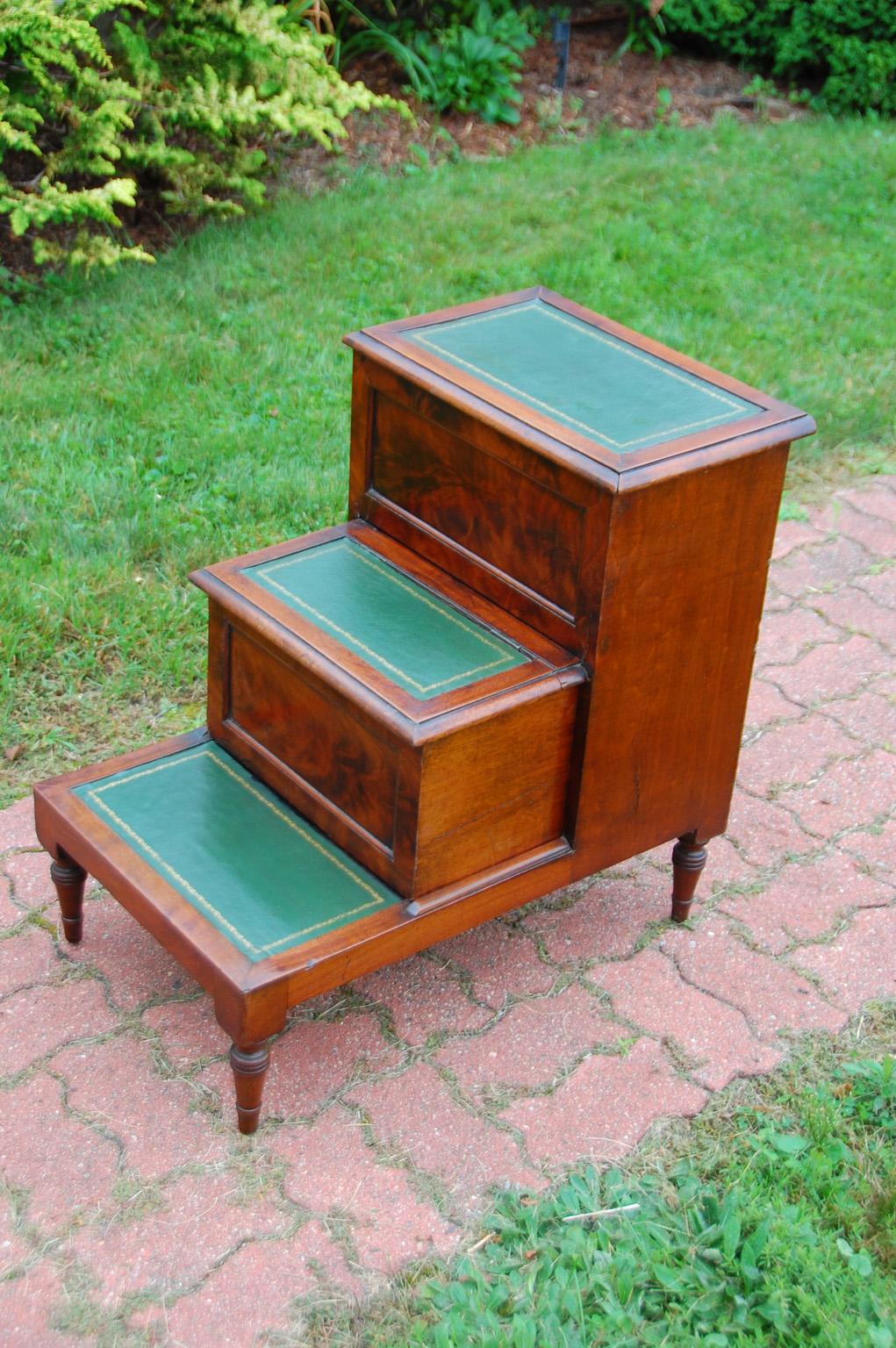 English Regency period flame grain mahogany converted bedstep commode with hand dyed and tooled leather treads. The central step has been converted to a drawer, the tread hinges up, the step slides out and full access to the space is available. The