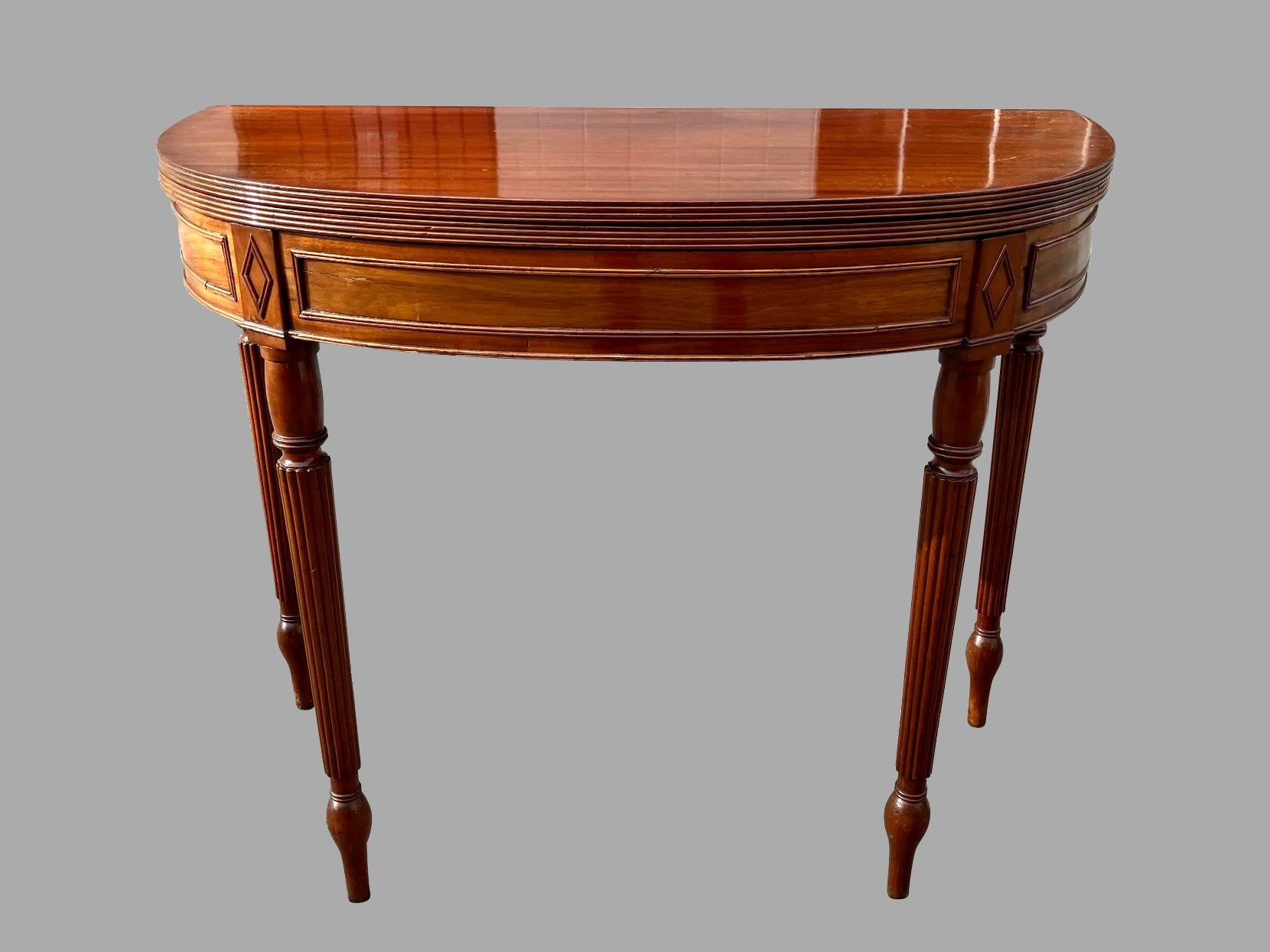A fine English Regency period flip top games table, the solid mahogany top with a reeded edge above a curved base embellished with mouldings, all supported on reeded legs ending in elongated toupie feet. The top folds open and is supported by 2