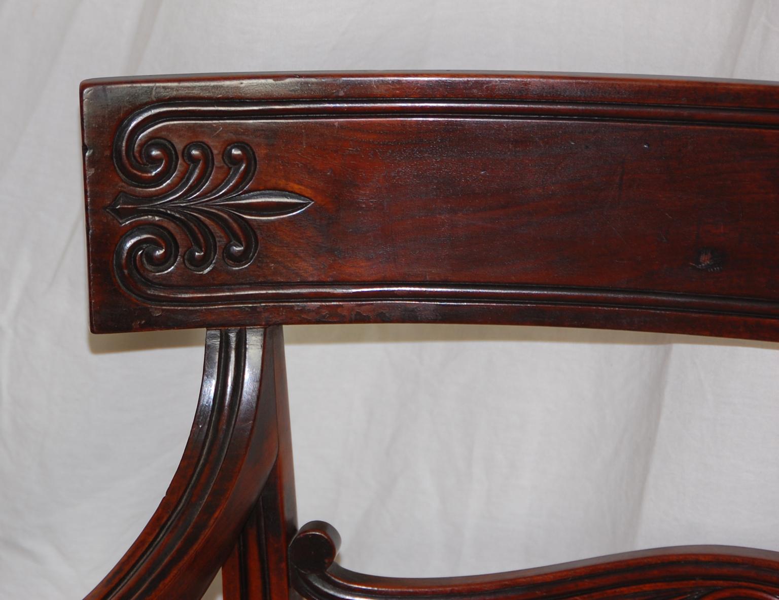 English Regency period pair of mahogany armchairs with bold scrolling arms, carved back and reeded legs. The overupholstered seats are freshly done in ultrasuede; the timber is of exceptionally high and dense quality mahogany, circa 1815.