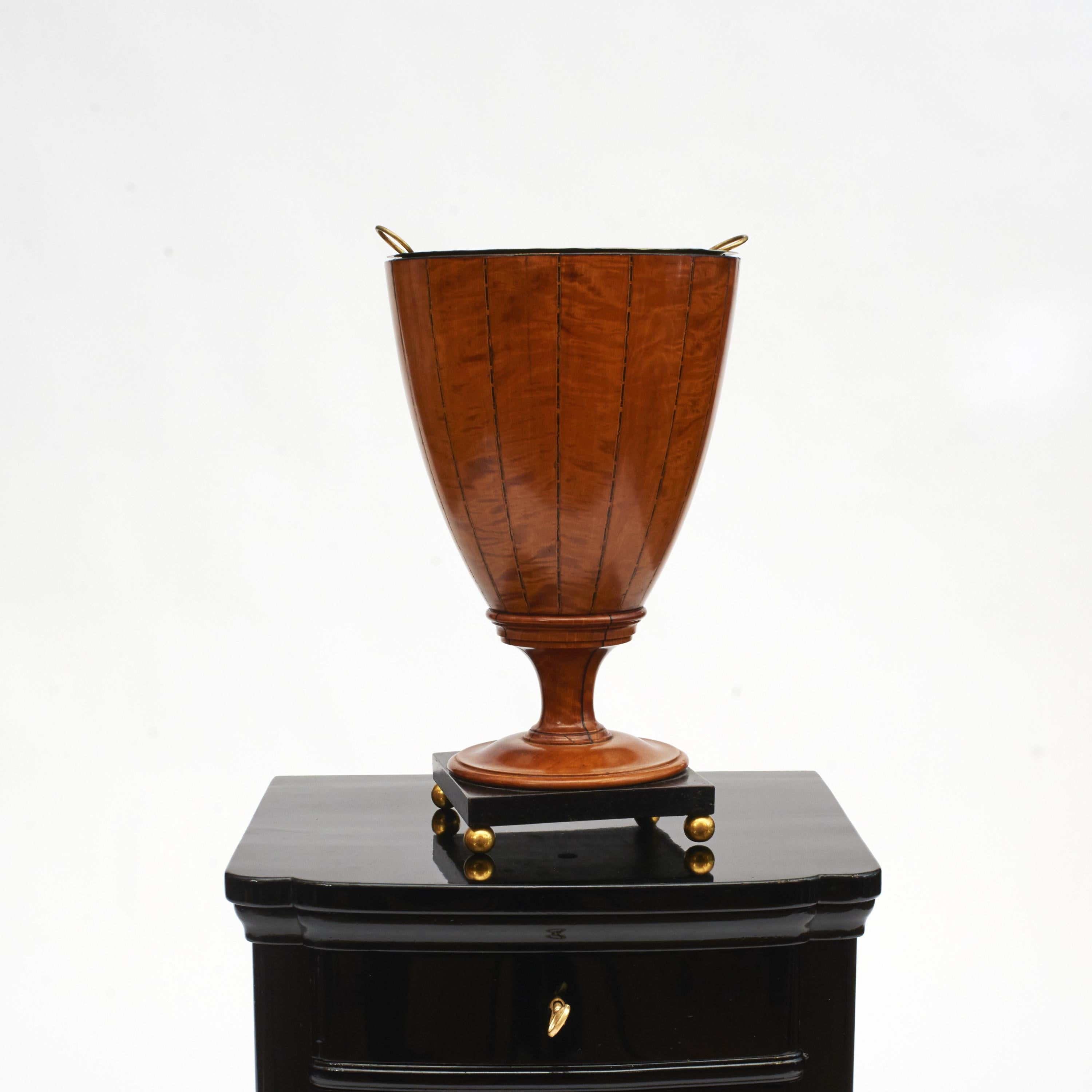 A very fine quality English Regency period wine cooler.
Made of maple with inlays in walnut and satinwood. Brass insert with handles. Raised on ebonized wooden base with brass ball feet.
Original untouched condition.
England, 1810-1820.