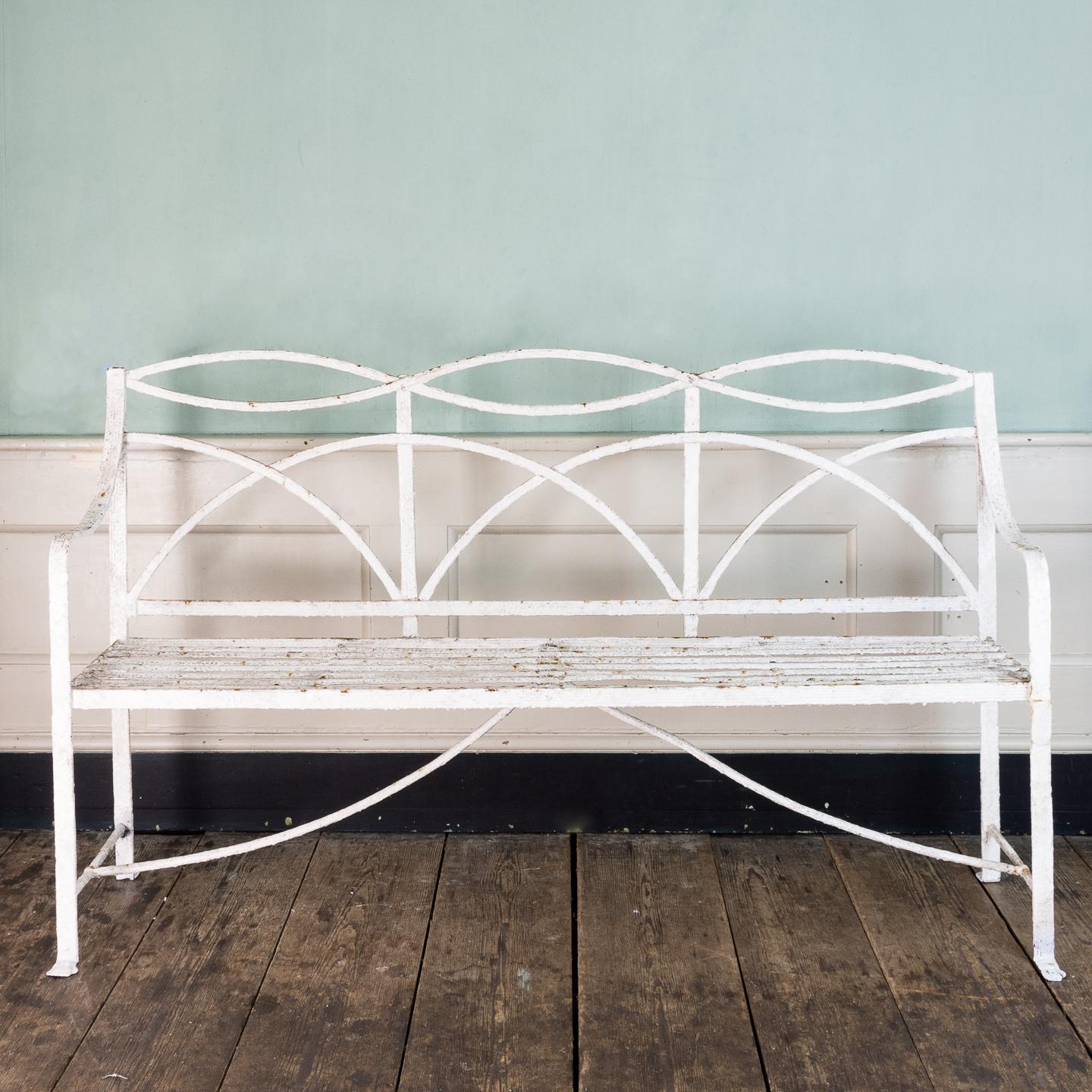 A Regency wrought iron bench or garden seat, of typical reeded and interlaced design, with paw feet to the front.