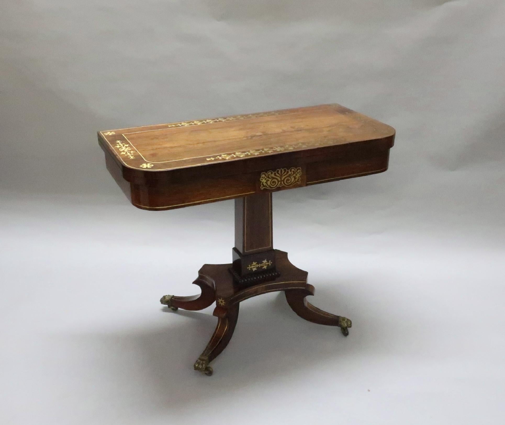 A very fine quality Regency rosewood and brass inlaid fold over games or occasional table with rectangular shaped stepped column and quarter beaded mouldings. The table has a shaped platform base and out swept tapering legs with brass string inlay