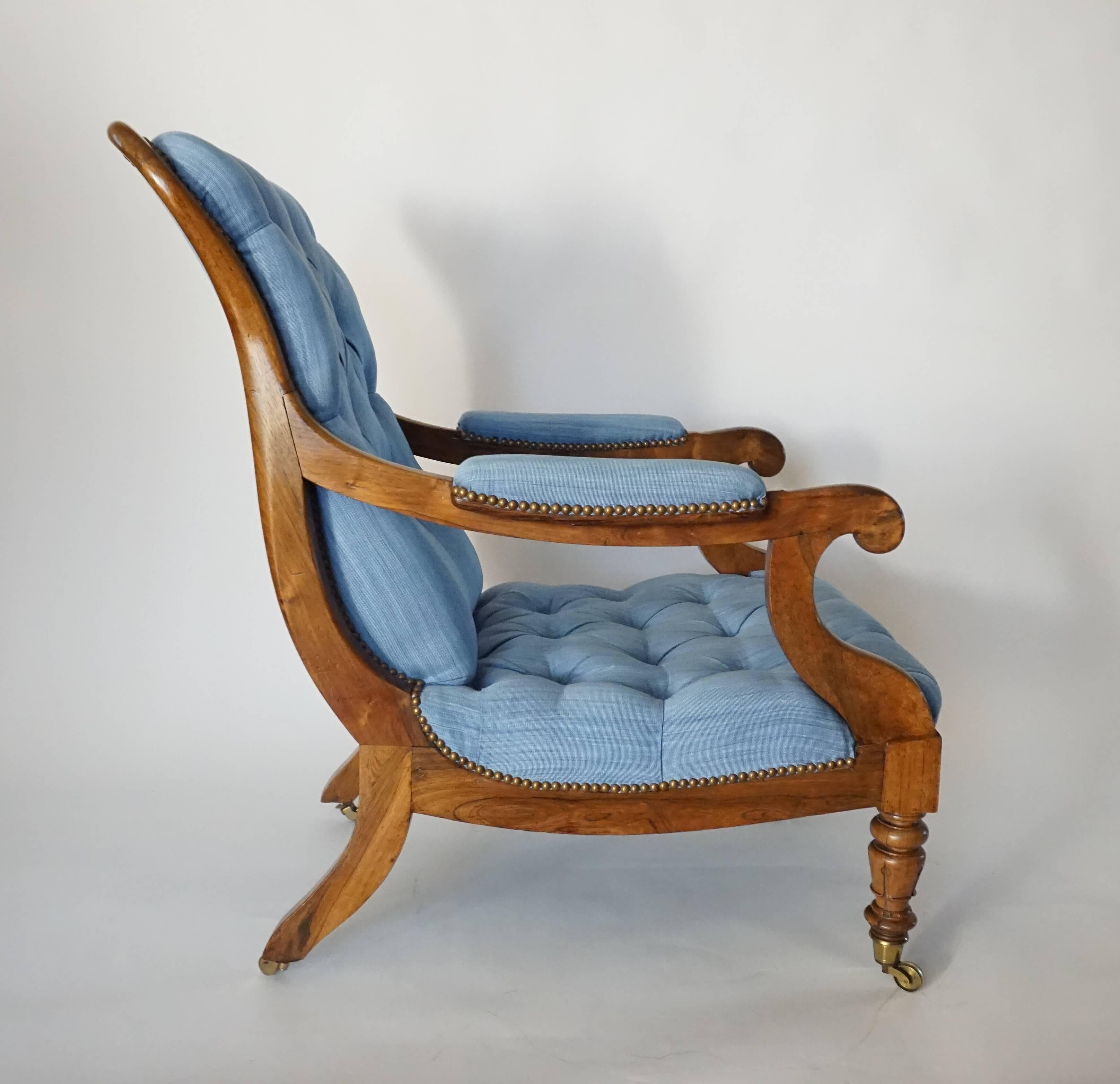 English circa 1840 late Regency style William IV / early Victorian period library or lounge chair of large size having tufted upholstery on solid carved walnut frame with serpentine crest-rail continuing into padded scrolled arms connecting turned