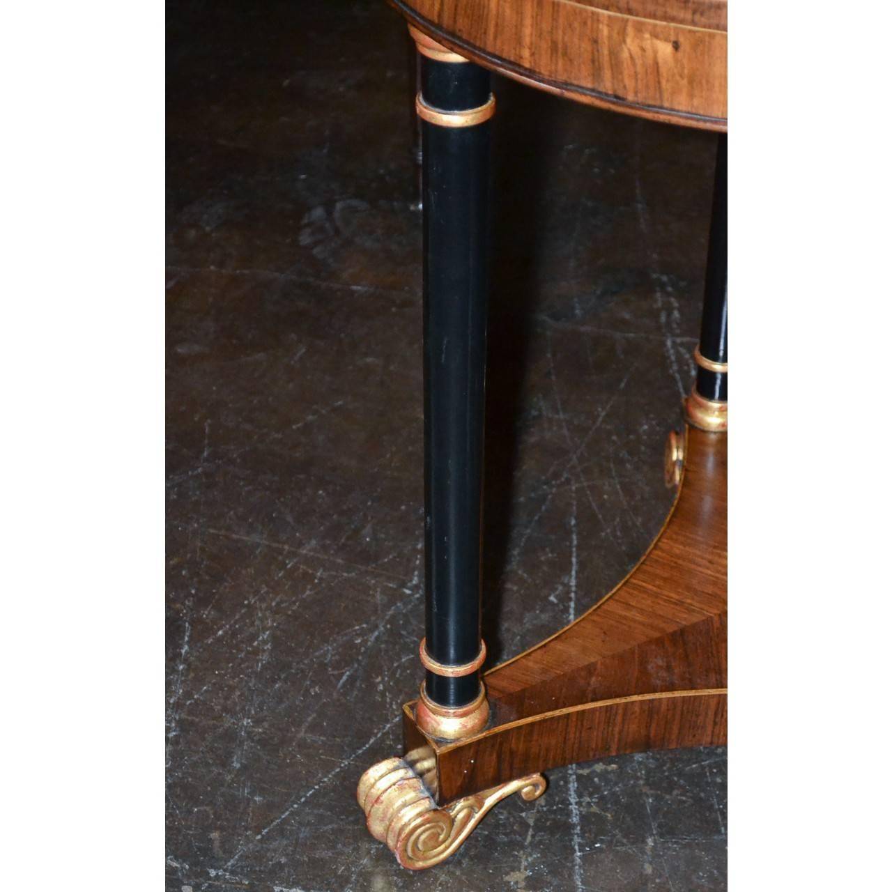 Superb 19th century English Regency rosewood circular top side table on turned ebonized columns with gilt trim accents and a tri-concave base. The entire on gold gilded acanthus scrolled feet,

circa 1890.
