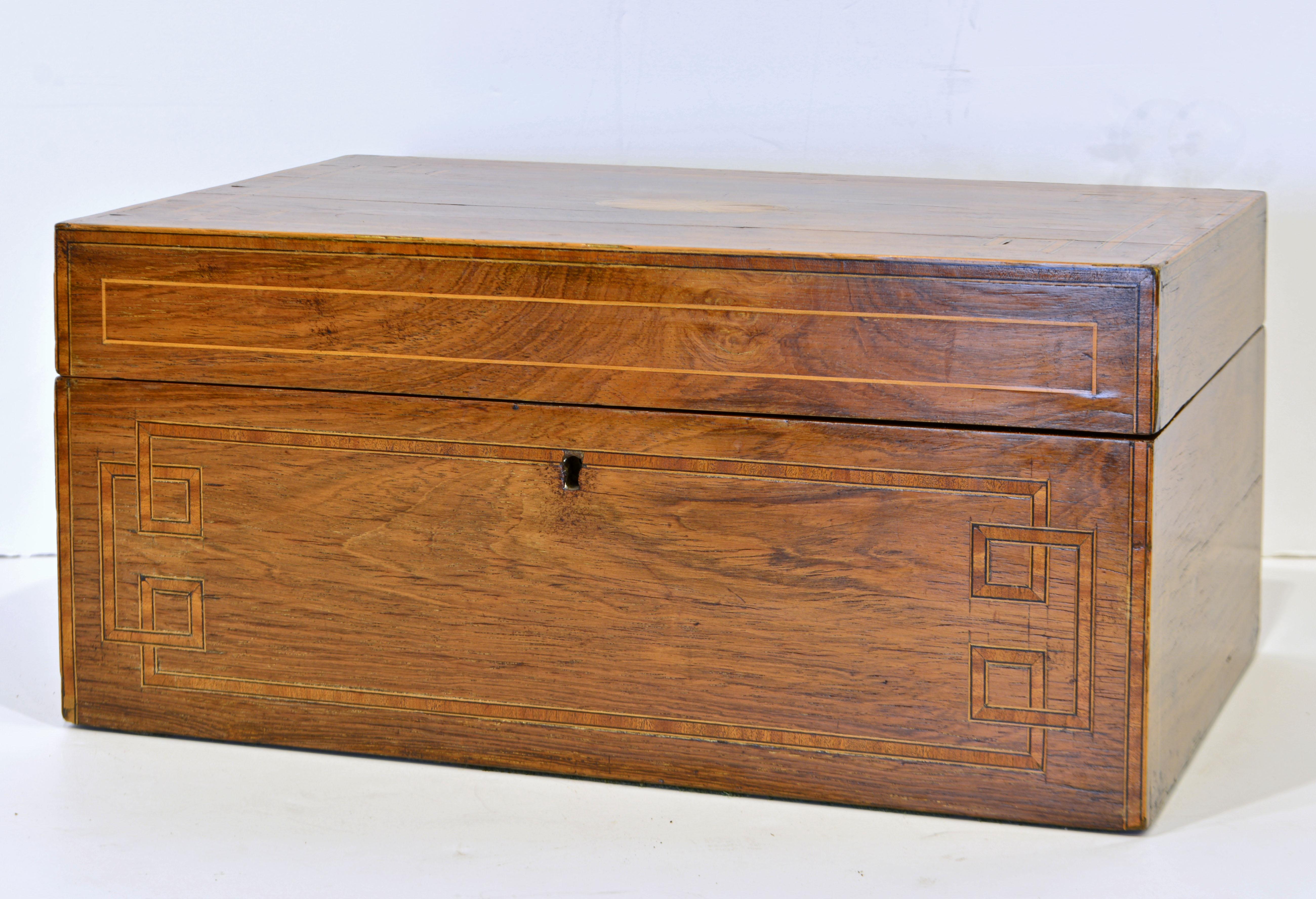 This regency mahogany table box features a delicate satinwood inlaid top in the classical style that opens up to an interior fitted with small compartments some of which have silk lined lids. The back of the top sports a silk lined paper compartment.