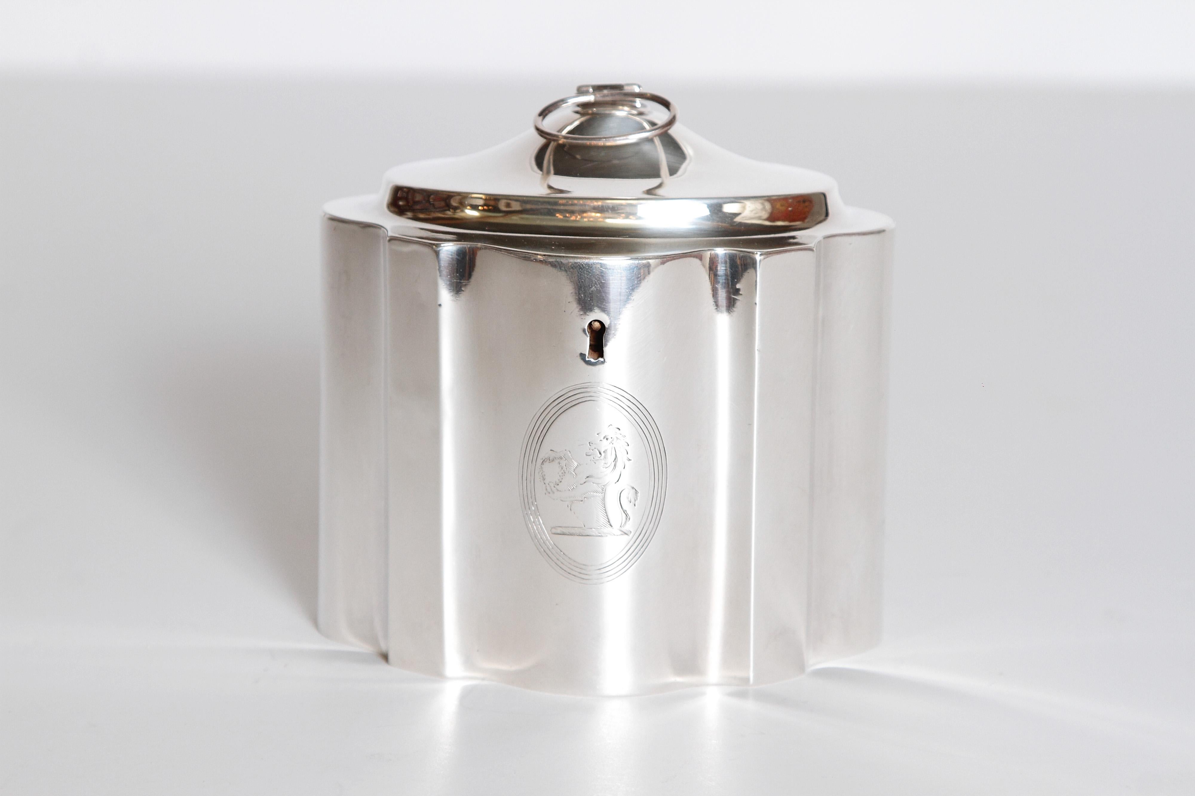 An English sterling tea caddy with scalloped lid and body. The lid has a ring pull. An engraved lion on the front side. Hallmarks on base.