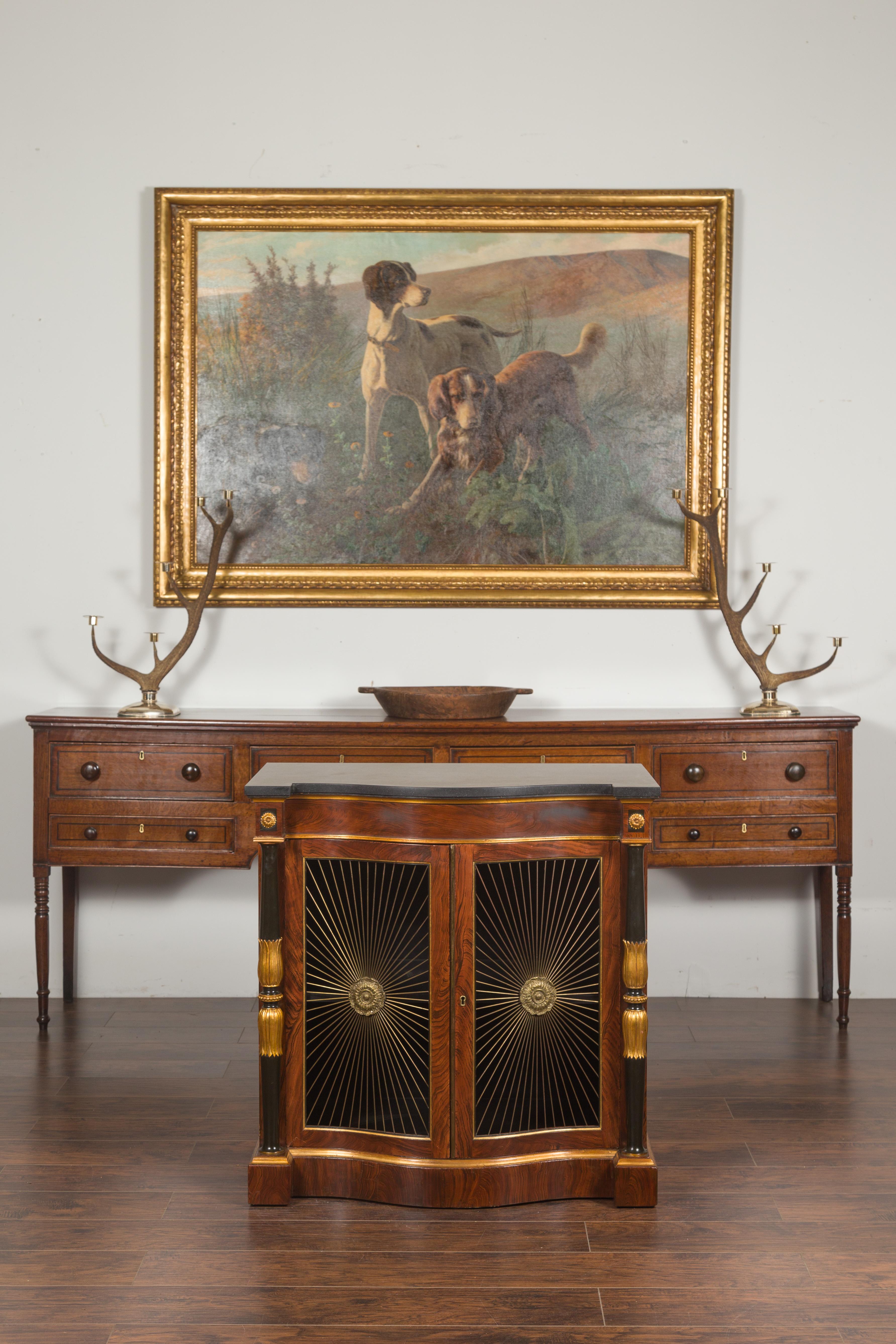 An English Regency style faux rosewood painted console cabinet from the early 20th century, with gilt accents and marble top. Created in England during the first quarter of the 20th century, this Regency style cabinet attracts our attention with its