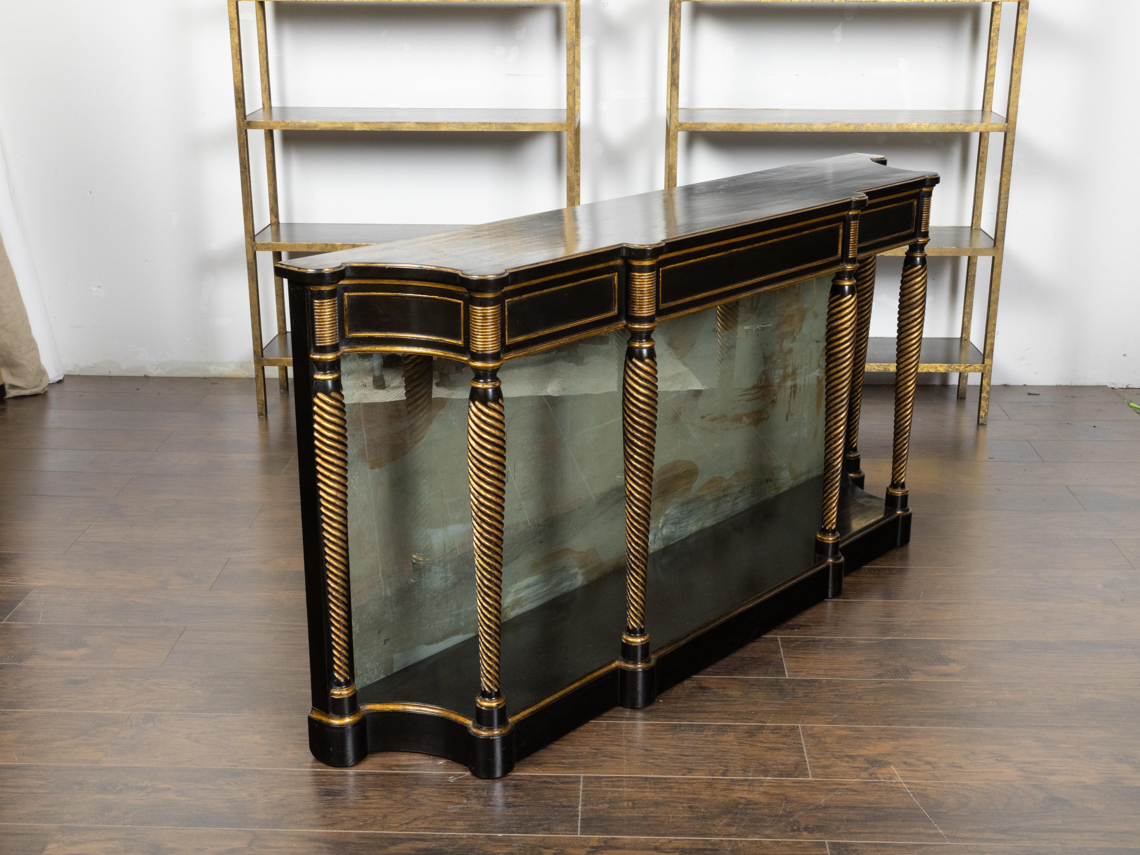 An English Regency style console table from the early 20th century, with ebonized wood, gilt finish and mirrored back. Created in England during the first quarter of the 20th century, this Regency style console table features a rectangular top with