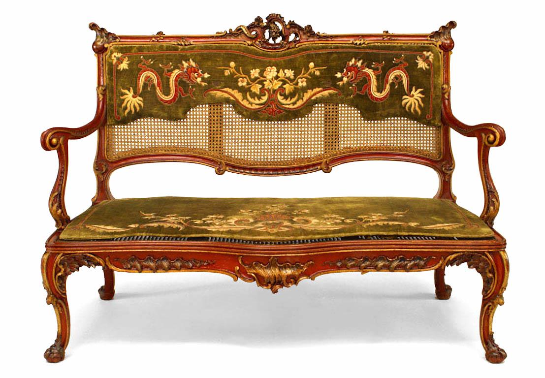 English Regency style (19th Cent) red lacquer and gilt trimmed loveseat with cane upholstery and green embossed back panel.
