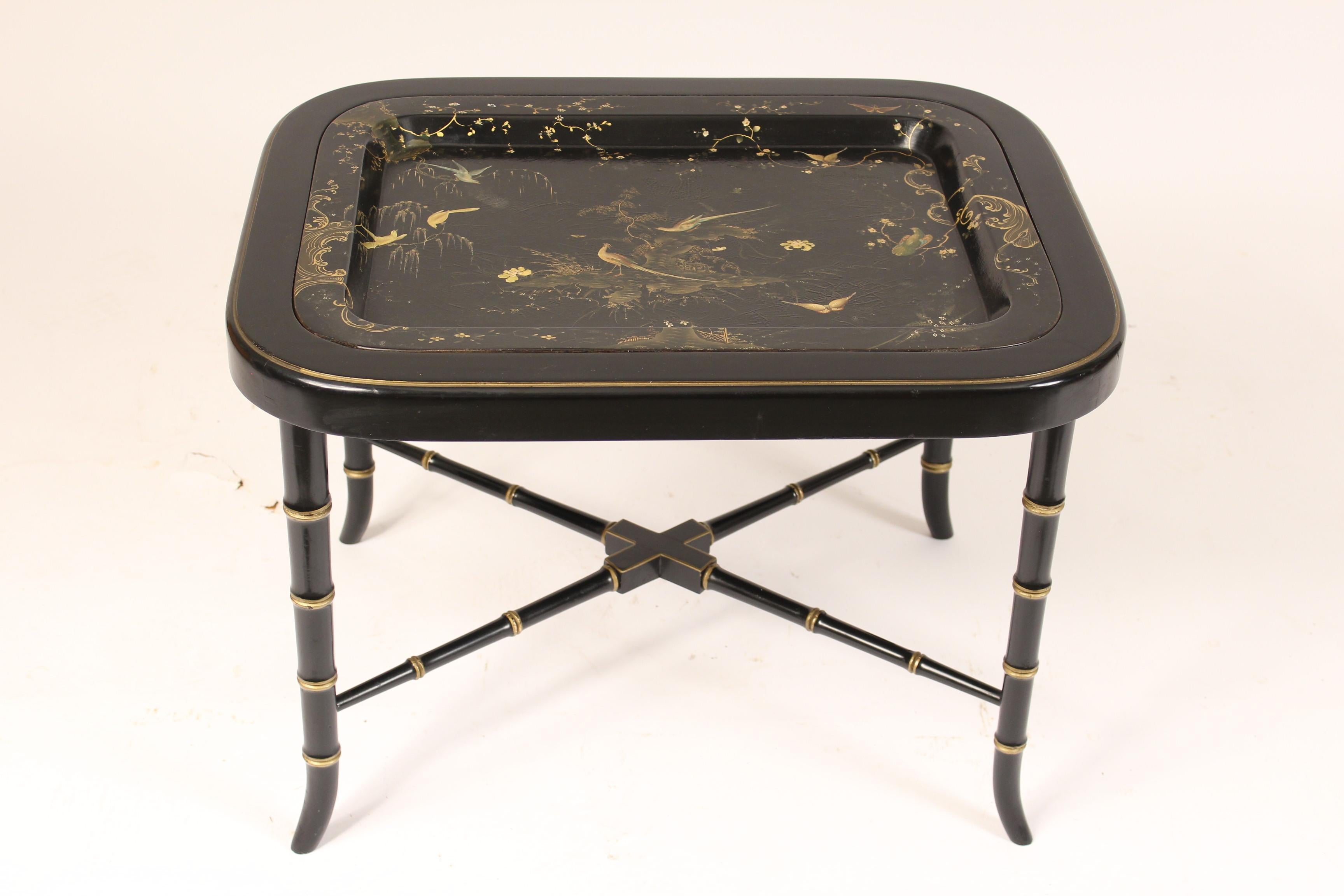 English regency style black lacquer and gilt decorated papier mâché tray table. The gilt decorated and painted papier mâché tray was made circa 1900. The regency style bamboo turned and gilt decorated base was made circa late 20th century. The