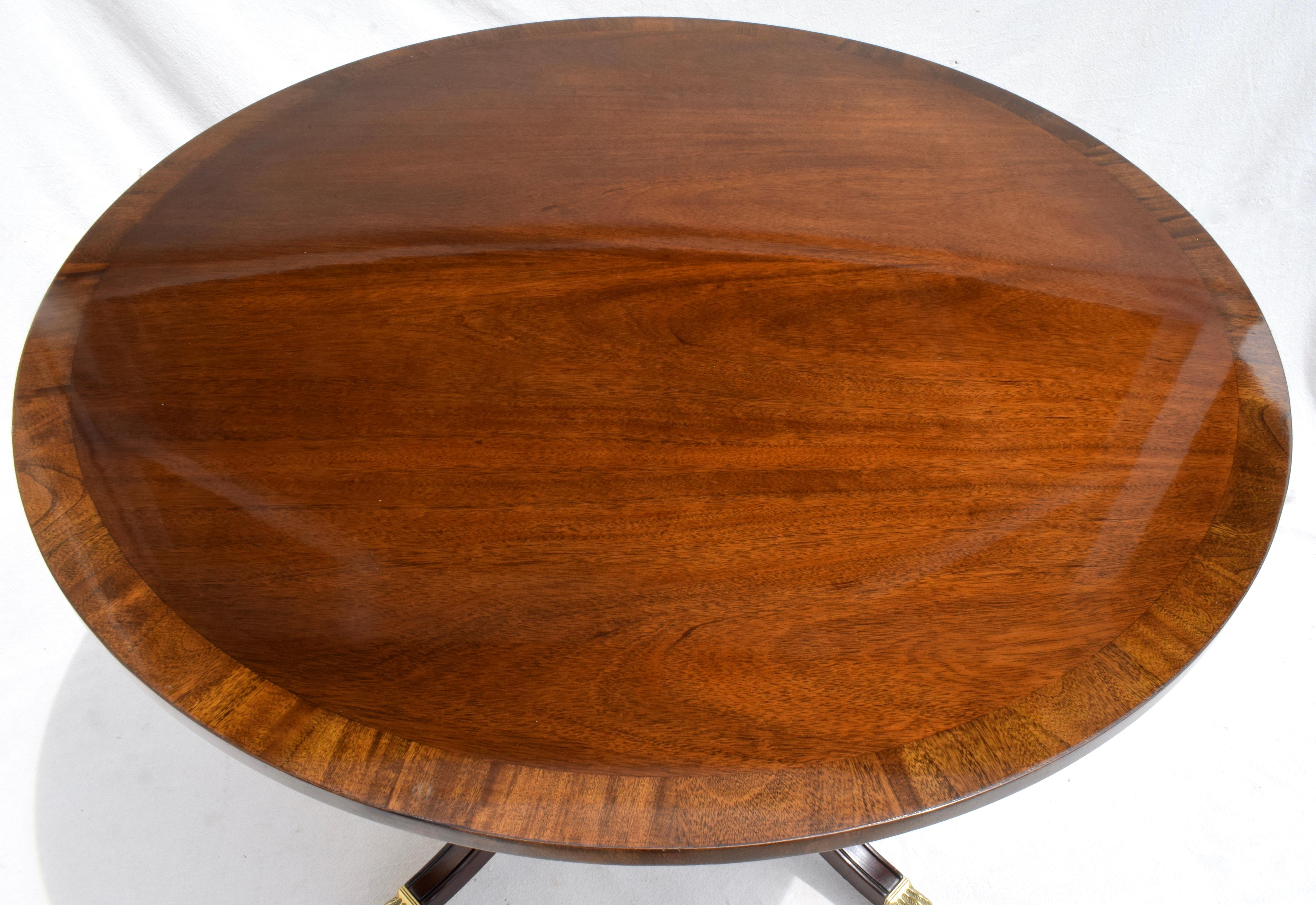 Baker Furniture Regency style banded Mahogany center table on brass casters with newly polished high finish to the top. Heirloom quality in excellent vintage condition.