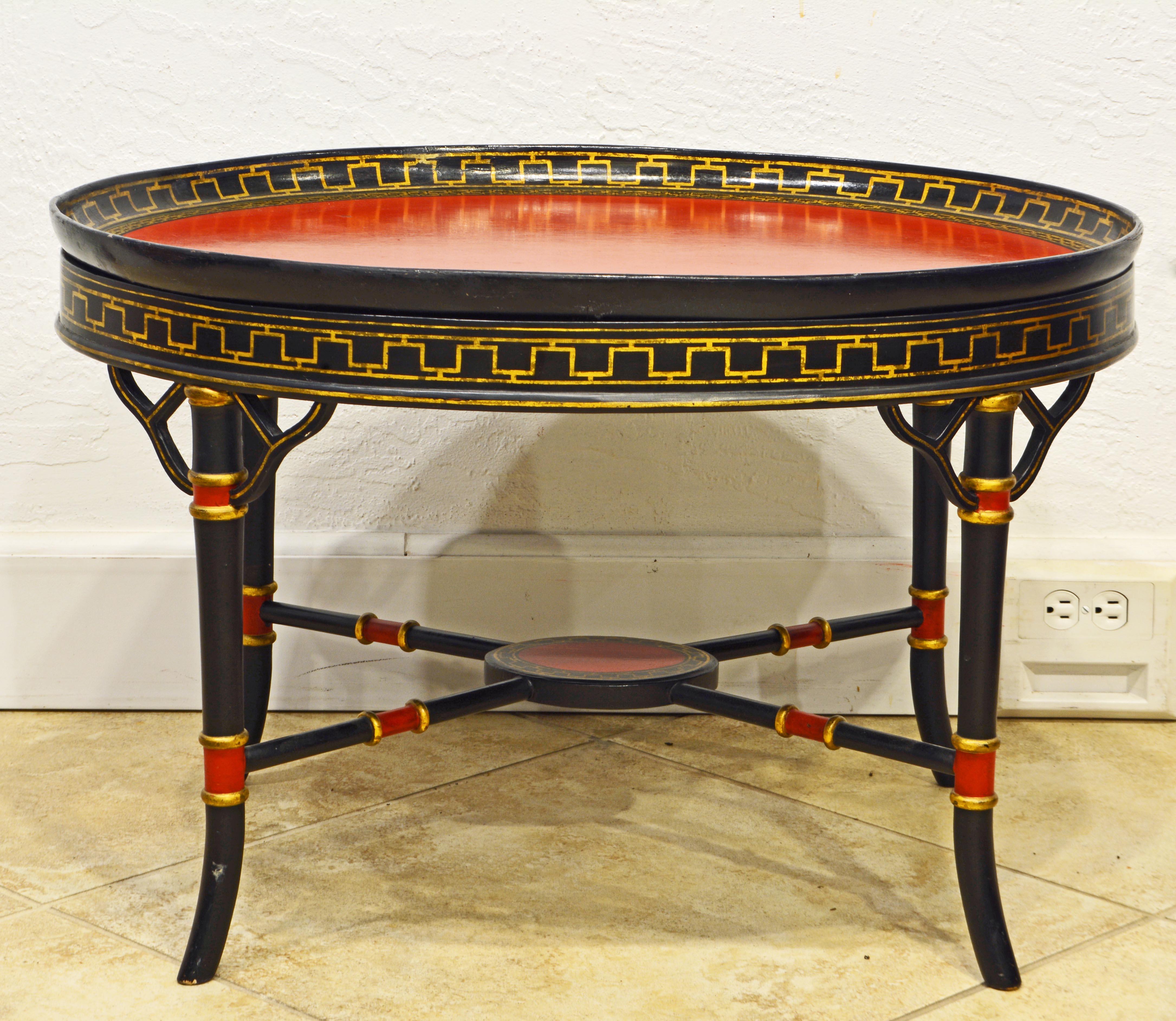This lovely English Regency style papier mâché tray table features a removable red lacquered tray top surrounded by a gilt decorated gallery sitting on an ebonized bamboo turned base with red and gilt accents. The legs are united by X-stretchers
