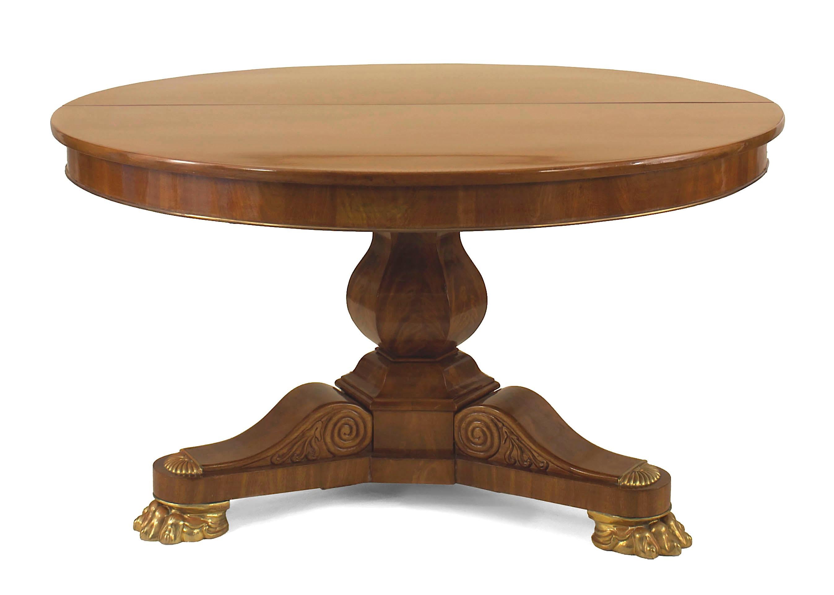 2 English Regency-style mahogany round (extension) dining tables with a tripartite carved scroll design pedestal and brass trim and replaced claw feet. (Each table has 2-30