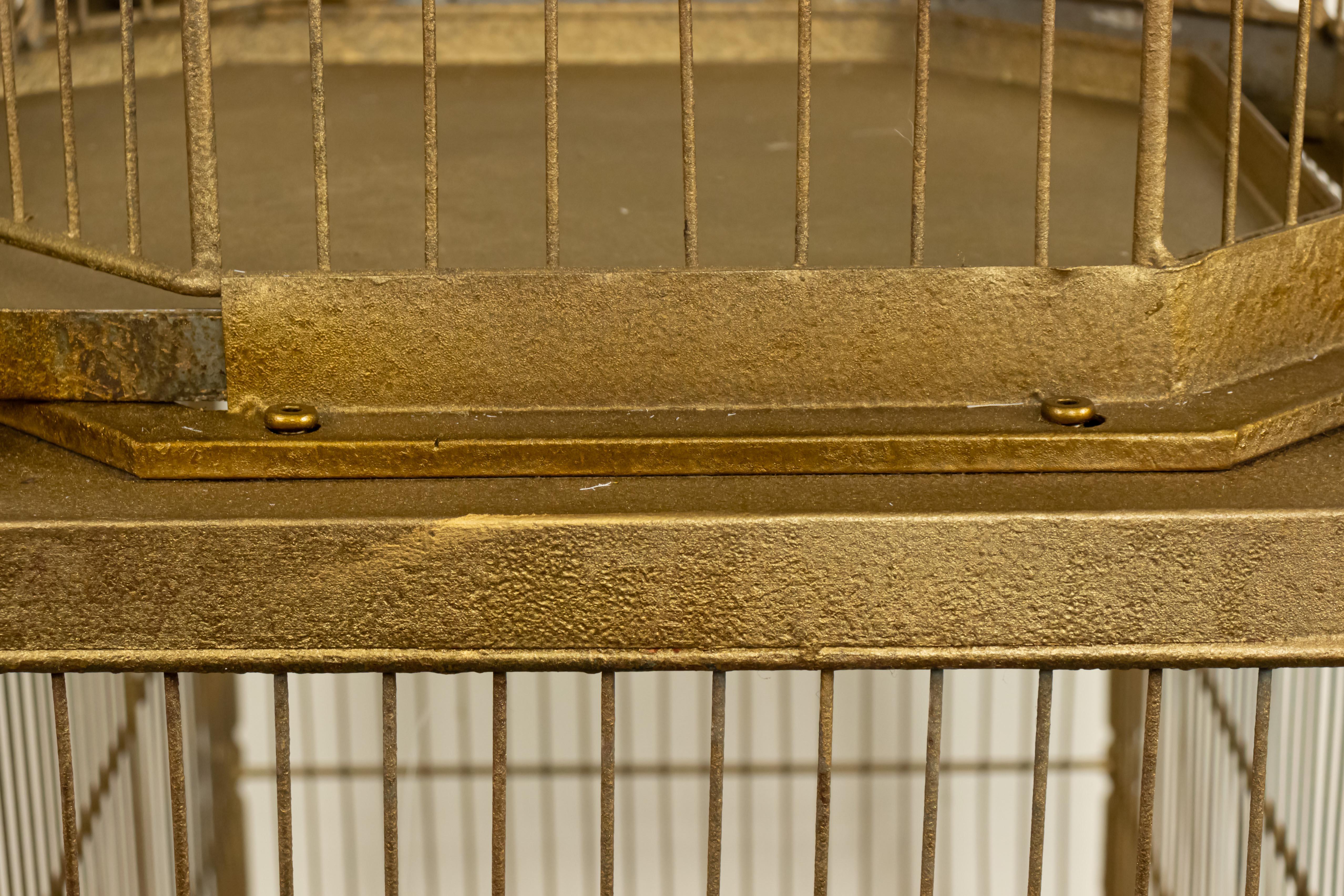 English Regency style bird cage with gilt metal bars and structure, two domed upper cages and one large rectangular cage with finial decor, stretcher base, and pull out drawers beneath each compartment.