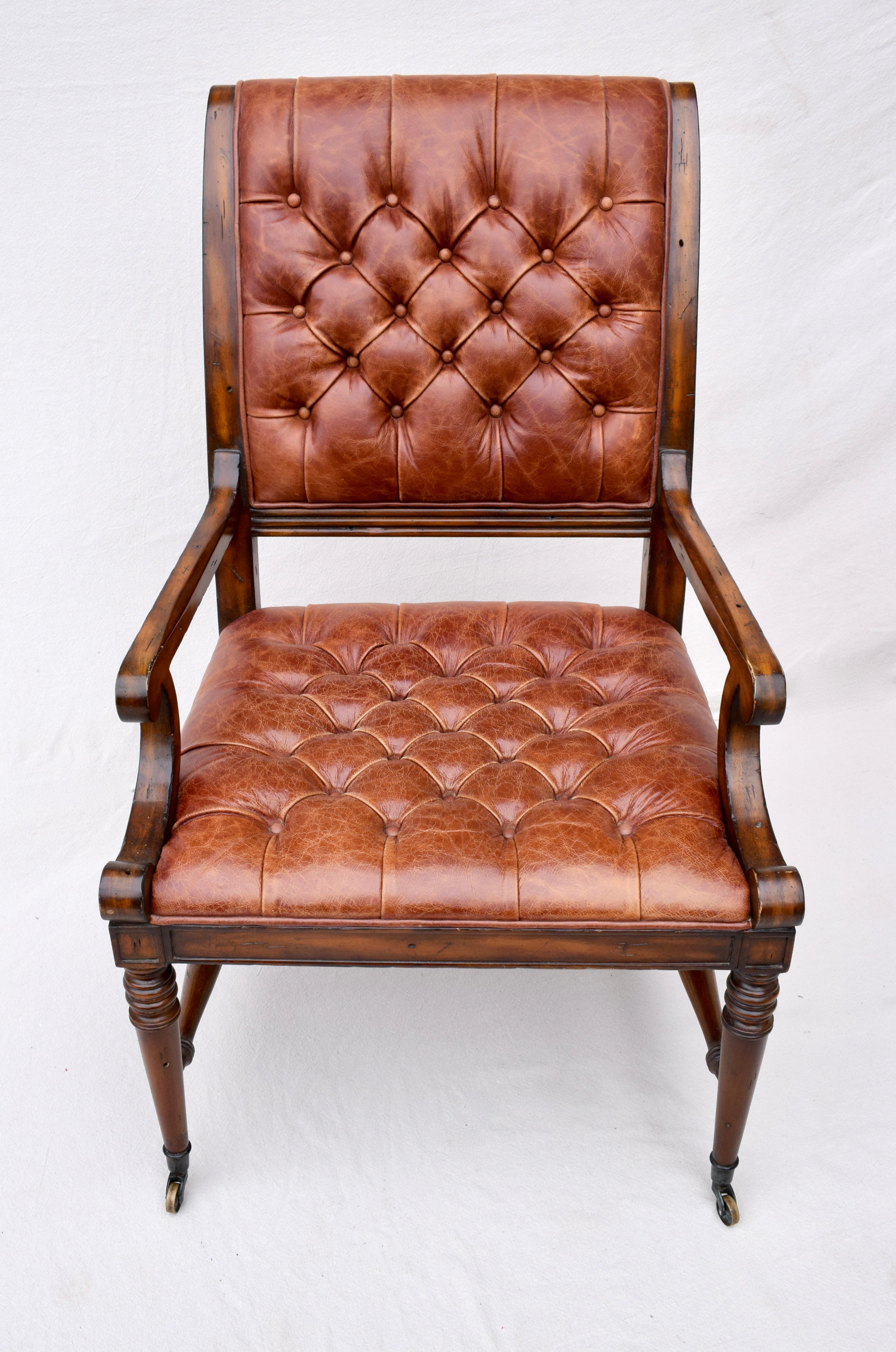 An impressive English Regency style open arm tufted leather library chair on brass casters in rarely if ever used condition. Maker unknown, in the styles of Beacon Hill & Baker Furniture Company.