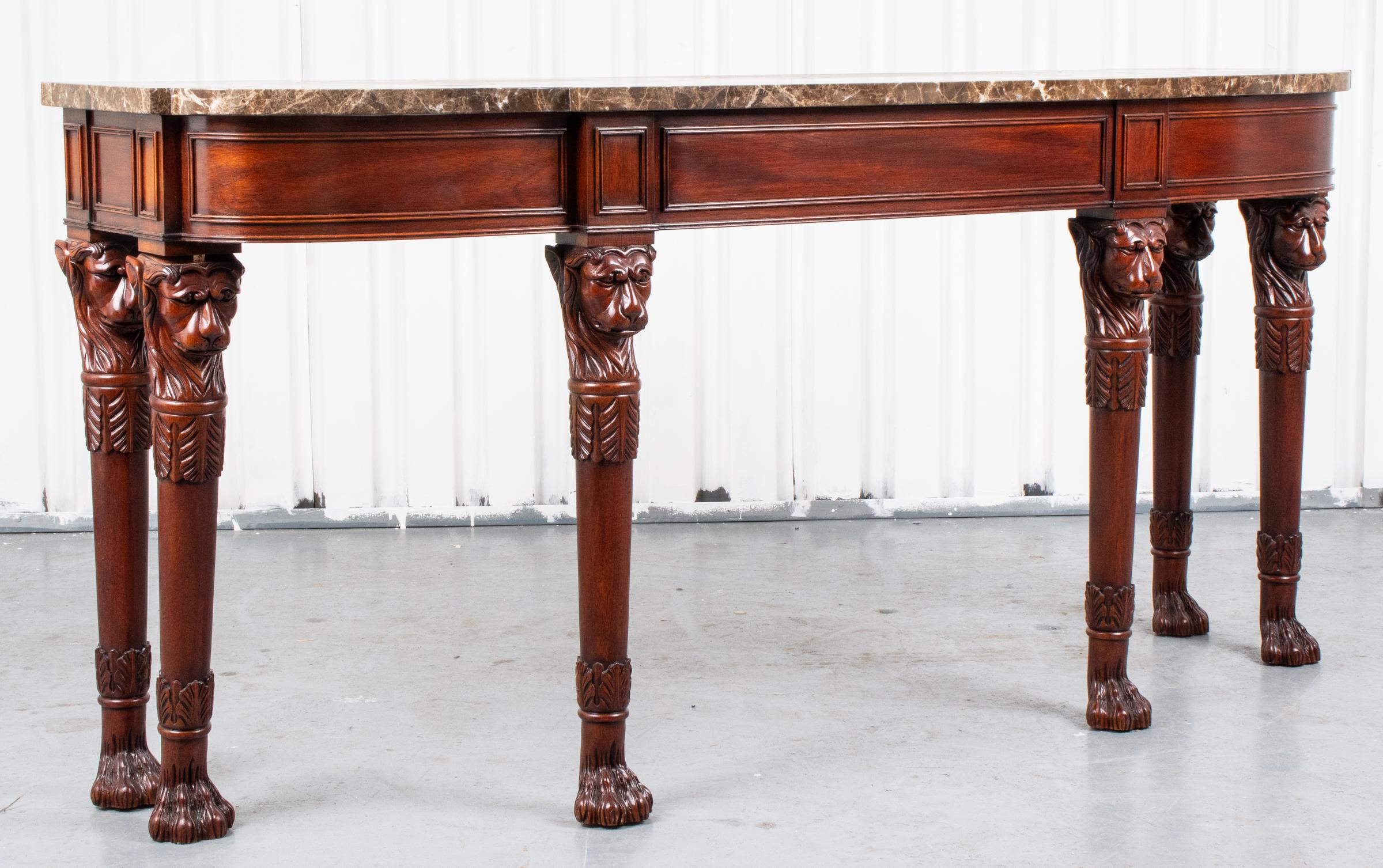Regency style mahogany console table, 20th century, in the Irish taste, the marble top over the frieze with wainscot details raised on legs with carved lion head motifs terminating on hairy-paw feet. Measures: 34” H x 72” W x 19.5” D.
