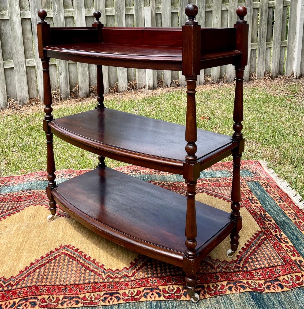 English Regency style mahogany three tier dessert buffet

Fabulous 19th century mahogany three-tiered buffet trolley or server. The wood shelves are supported by four turned leg columns with round ball finials at the top and porcelain casters on the
