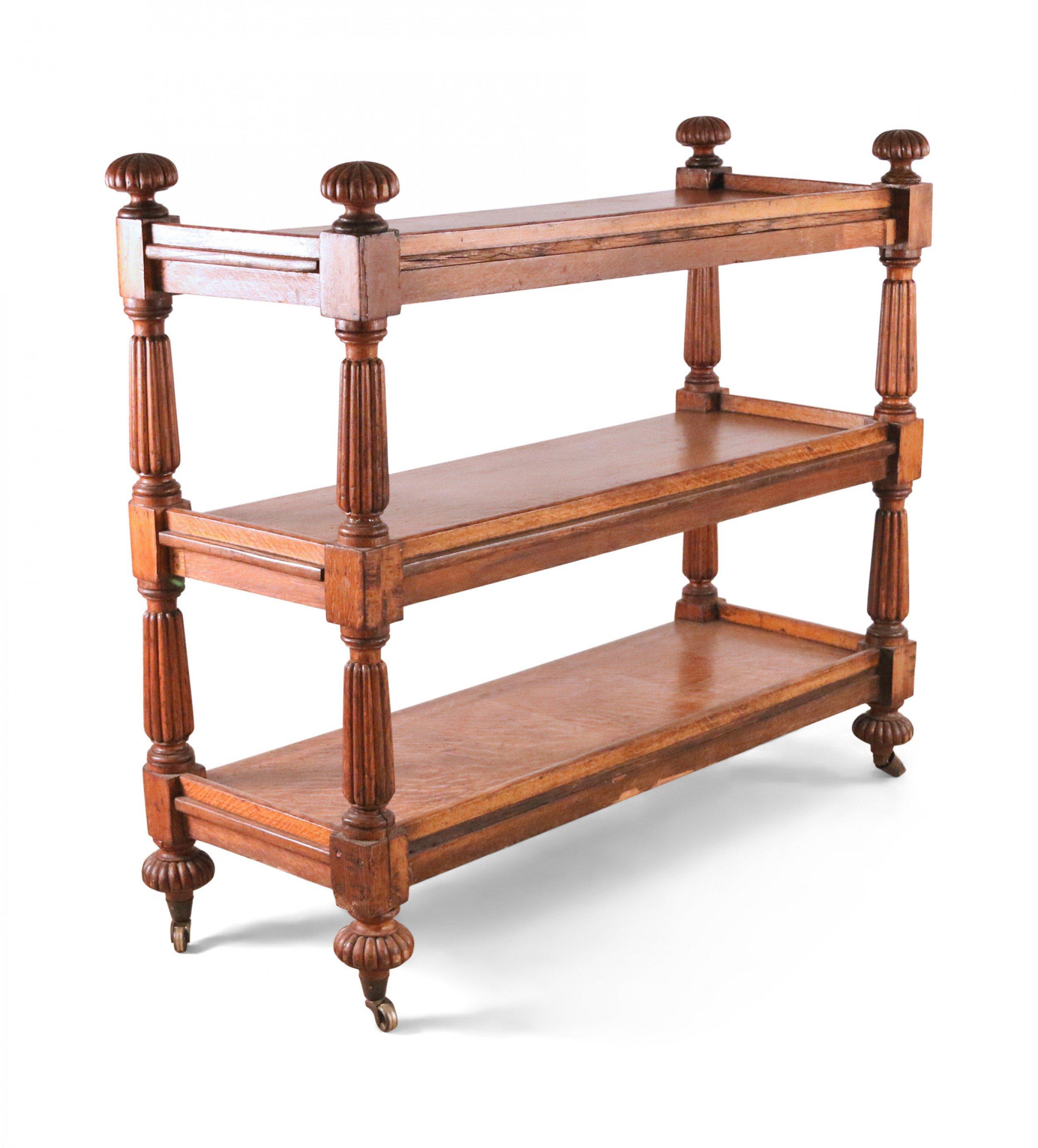 English Regency style oak three shelf étagère with reeded ball finials and supports on casters.
 