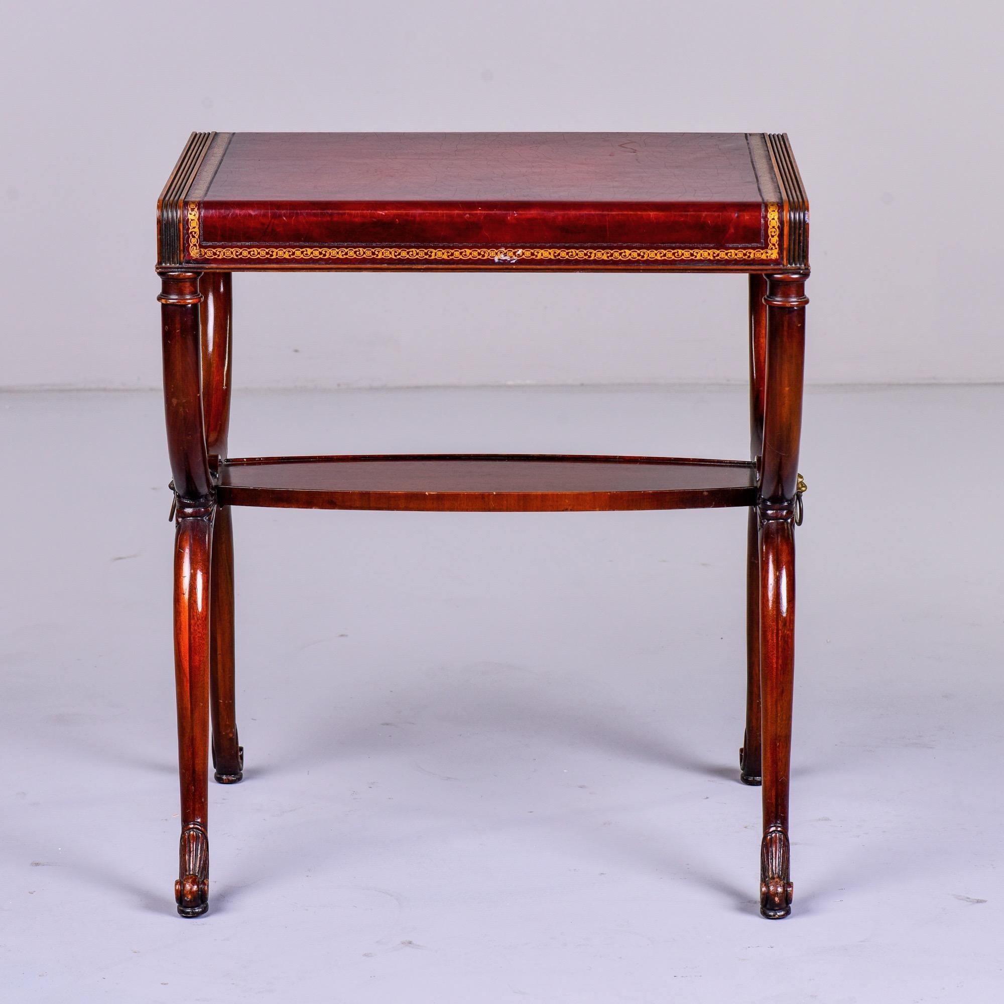 English Regency style side table in mahogany with curule base, brass lion head ornaments and leather top with tooled gilt trim, circa 1950s. Weiman Heirloom maker’s mark found on underside. 

Very good overall vintage condition with surface scuff