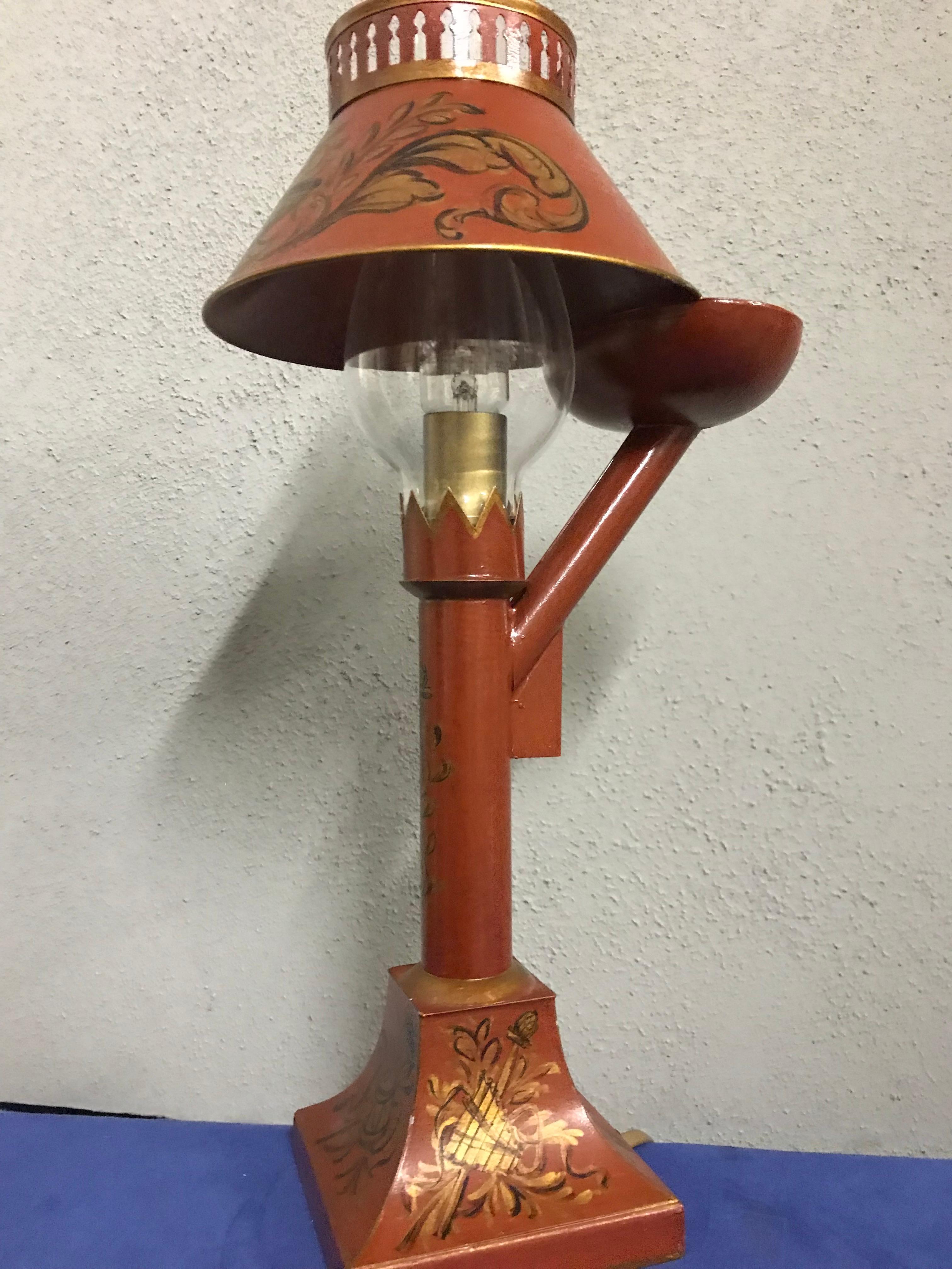 Exquisite English style small tole lamp By Gherardo Degli Albizzi featuring an oil lamp shape, with hand painted decoration all-over. On the base there are classical decoration such as musical instruments together with vegetals. The same decoration