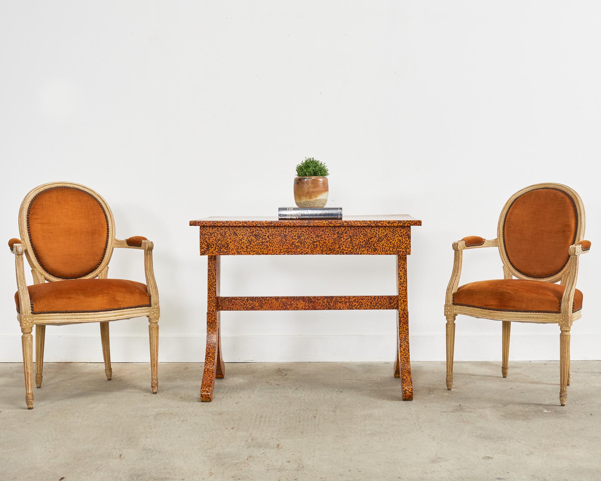 Diminuta mesa de escritorio o consola de estilo regencia inglés lacada moteada por el artista Ira Yeager (estadounidense, 1938-2022). Fabricada en pino, la mesa se apoya en una base de caballete con caprichosas patas separadas. Pintada