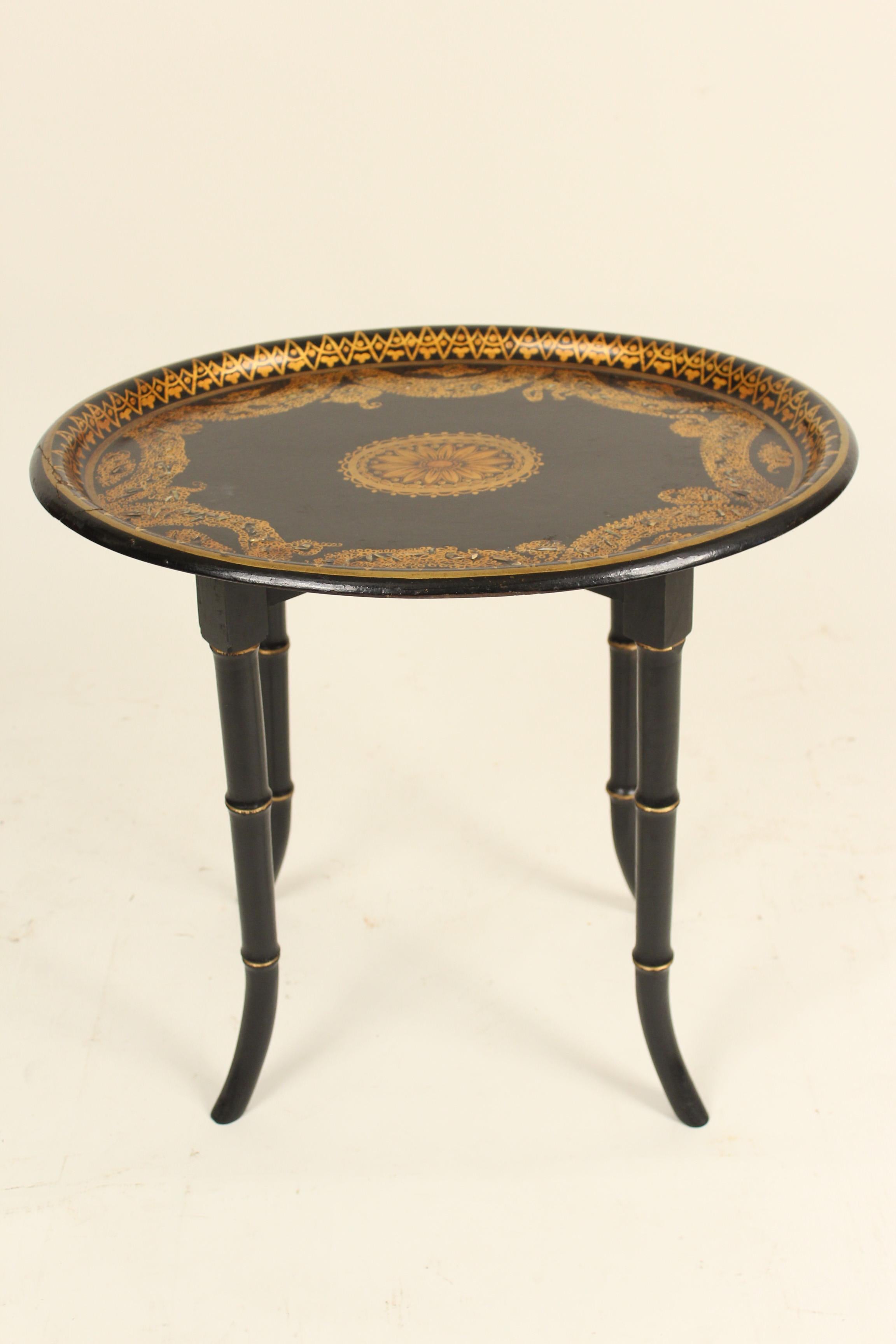 English Regency style late 19th century papier mâché tray on a late 20th century bamboo style stand. The tray has gilt decoration and mother of pearl inlay. The tray is attached to the stand.
