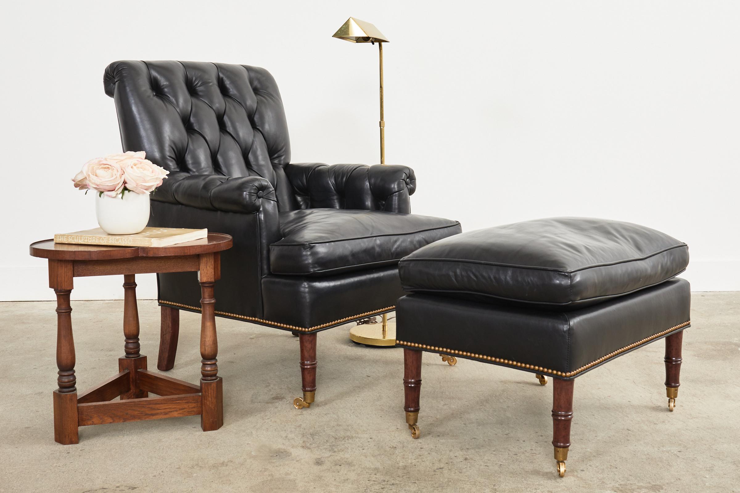 Handsome tufted black leather library armchair with matching ottoman. The chair features a walnut frame made in the regency taste with classic English rolled arms and a scrolled back. Covered with thick black leather hides having a tufted back and