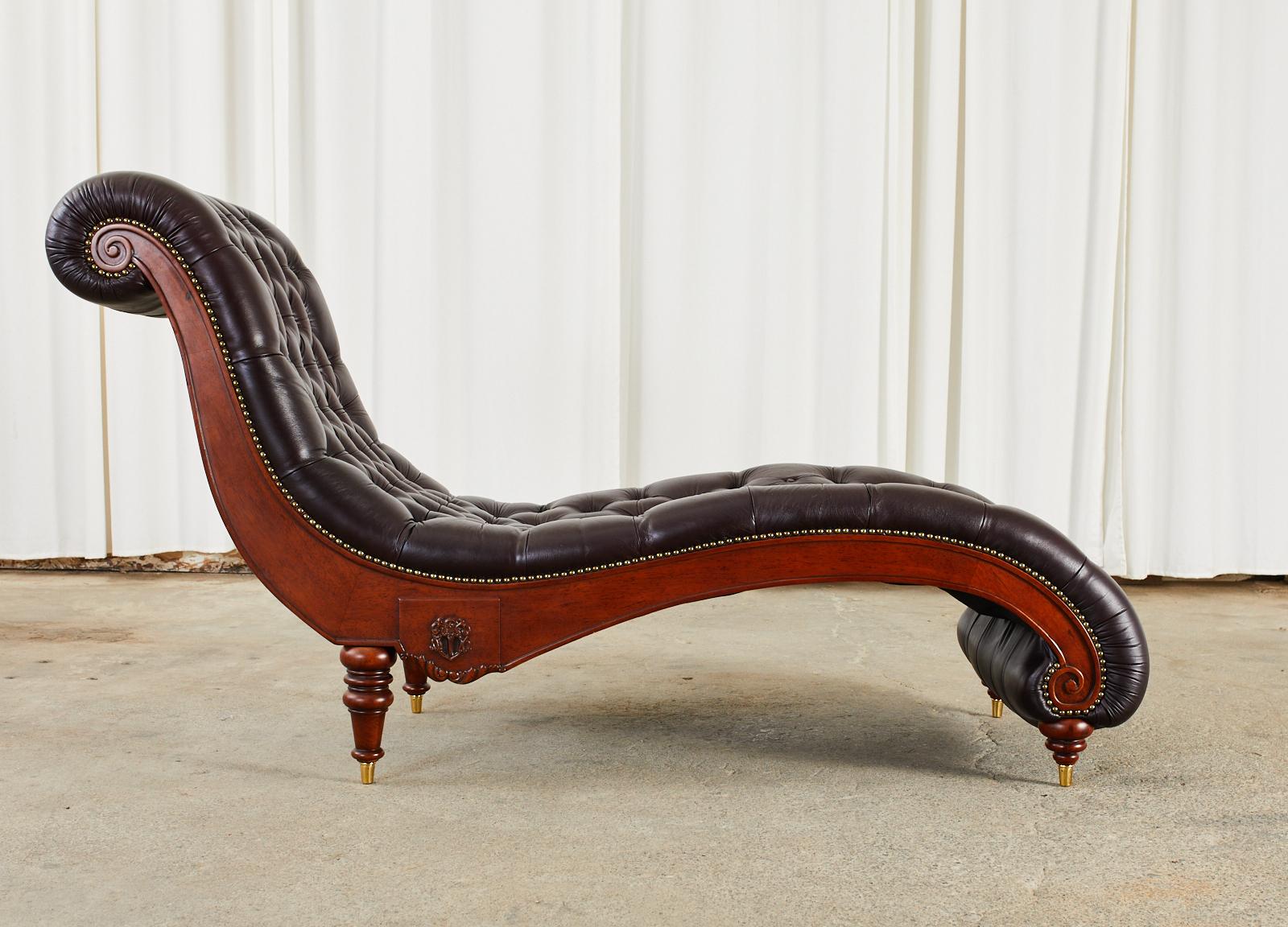 Opulent English regency style mahogany chaise lounge or chaise longue featuring a chesterfield style button tufted seating area with brass tack borders. The thick padded cordovan leather is amazingly comfortable with a body contouring design. The