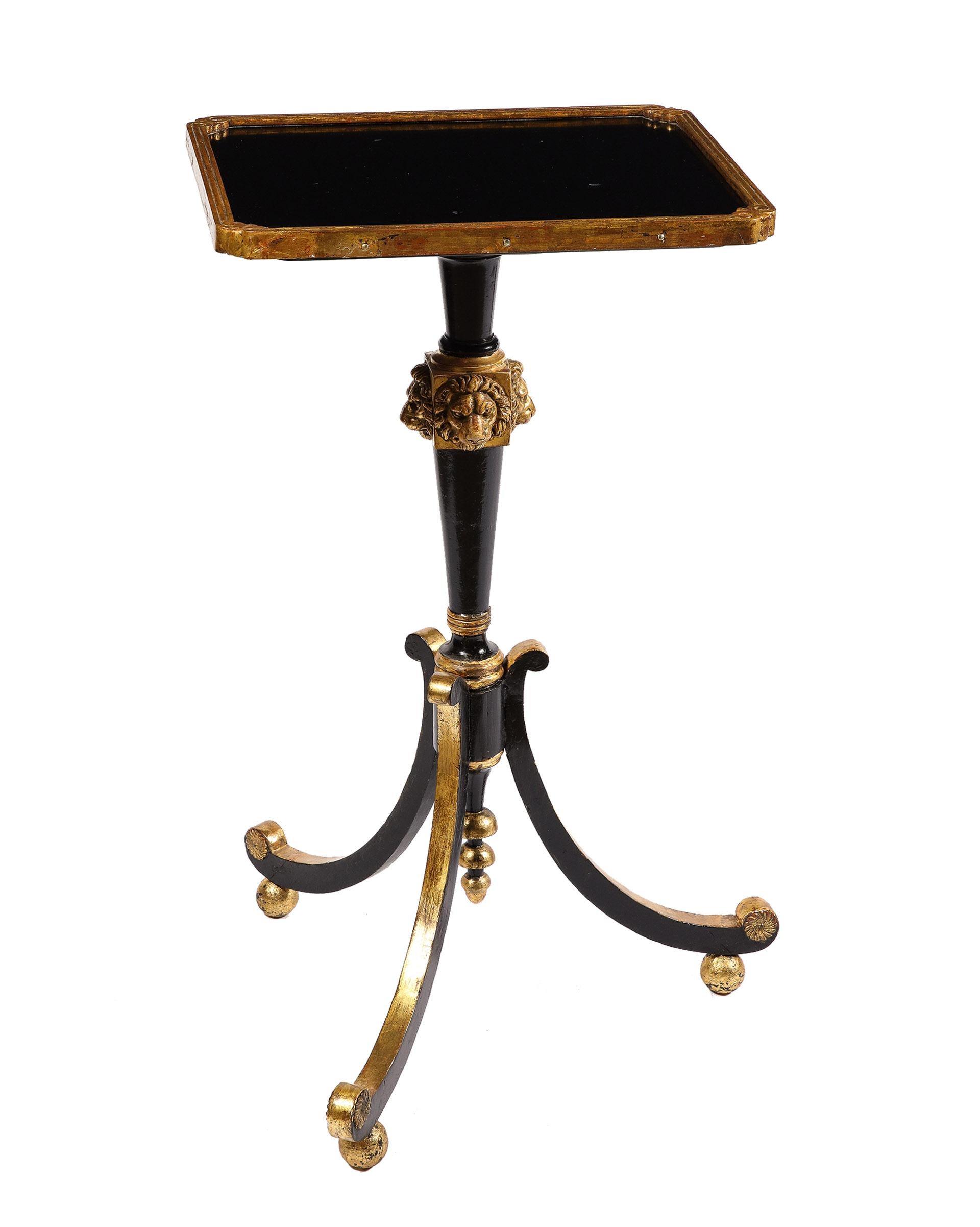 The Regency table with a gilt framed top supported by a central pedestal mounted with lion's heads all supported by three out-swept legs on ball feet.