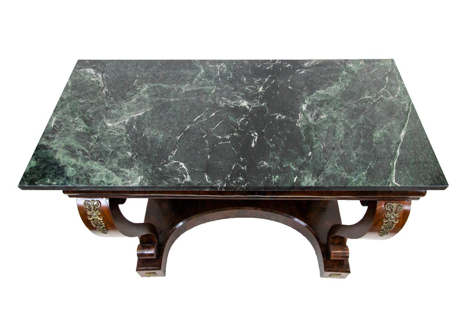 English Regency Verde marble top console table is fully veneered with crotch mahogany. The concave platform base has a mirrored back framed with ogee molding.