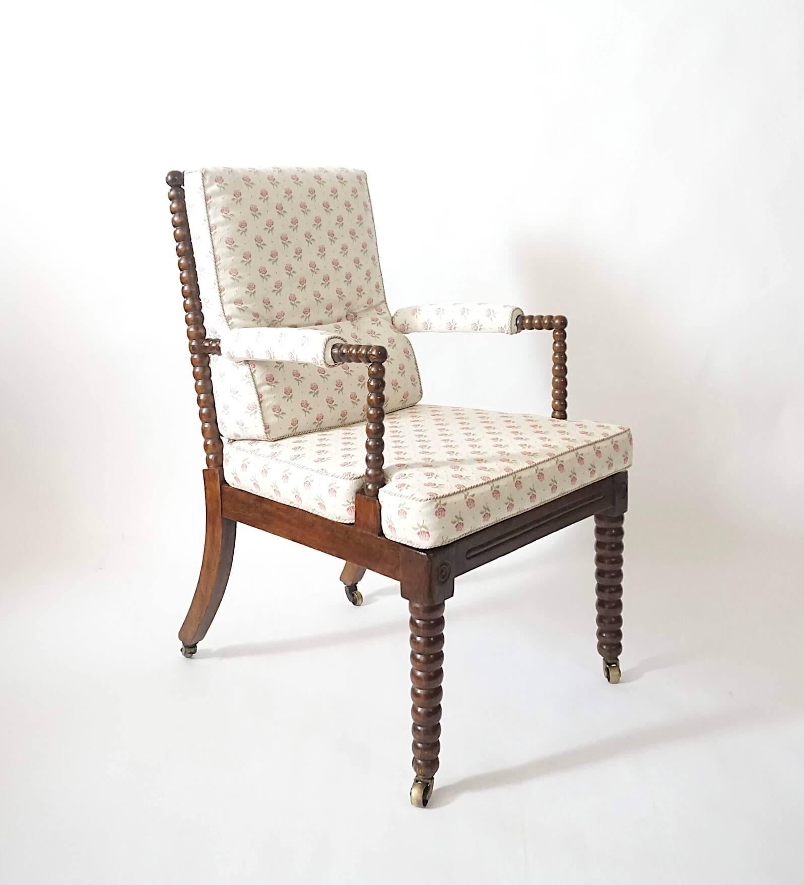 Magnifique et inhabituel fauteuil anglais d'époque George IV, datant d'environ 1825, dont la structure en noyer est entièrement sculptée de fuseaux tournés. Le dossier rectangulaire à quatre fuseaux de soutien et au coussin de dossier rembourré est