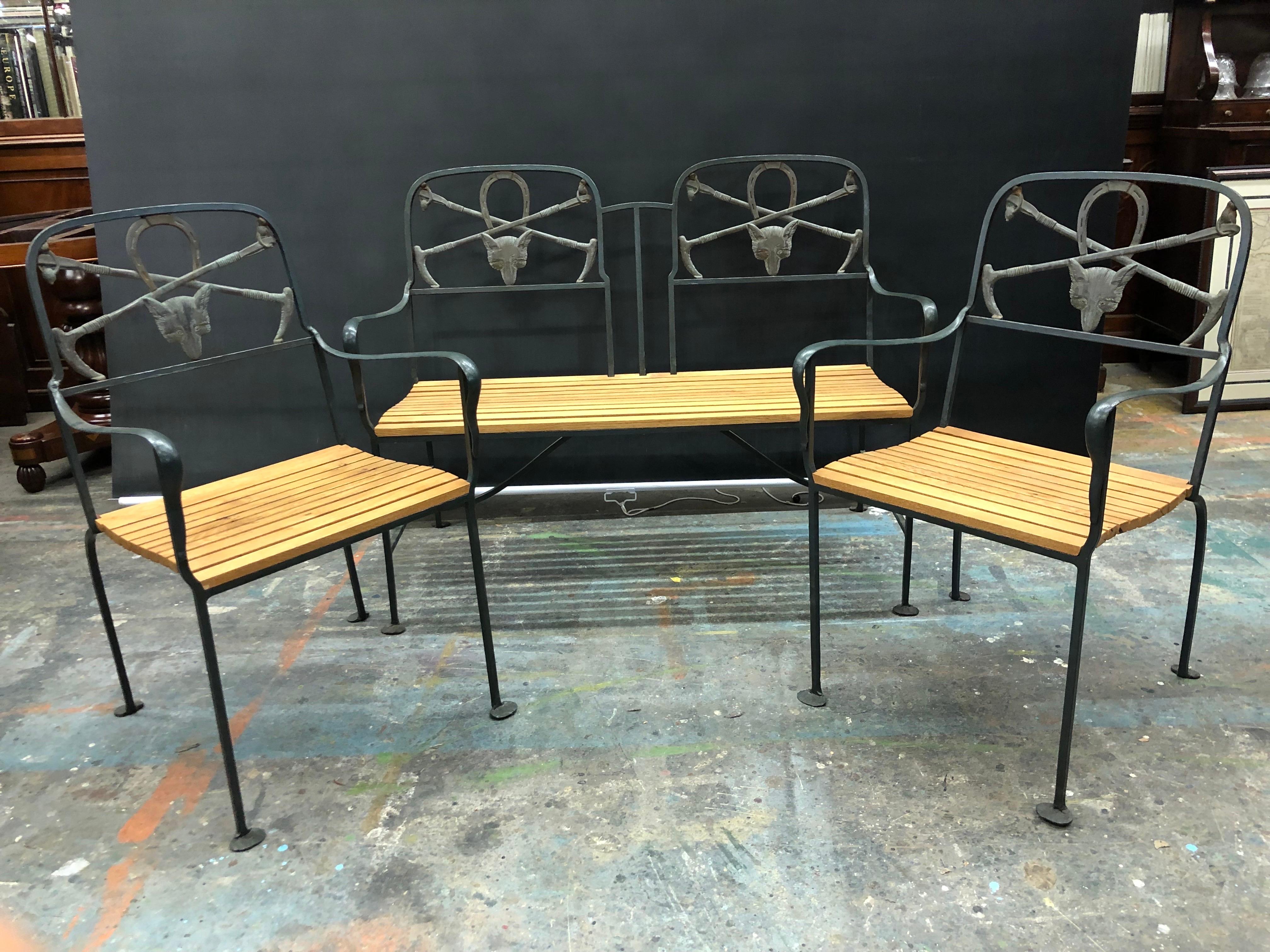This English Regency hand wrought iron and brass fox three piece garden set has oak plank seats and was made in the early 20th Century. The Regency Wrought Iron Bench has a double panel back with fine cast brass Fox Heads below a Horse Shoe in the