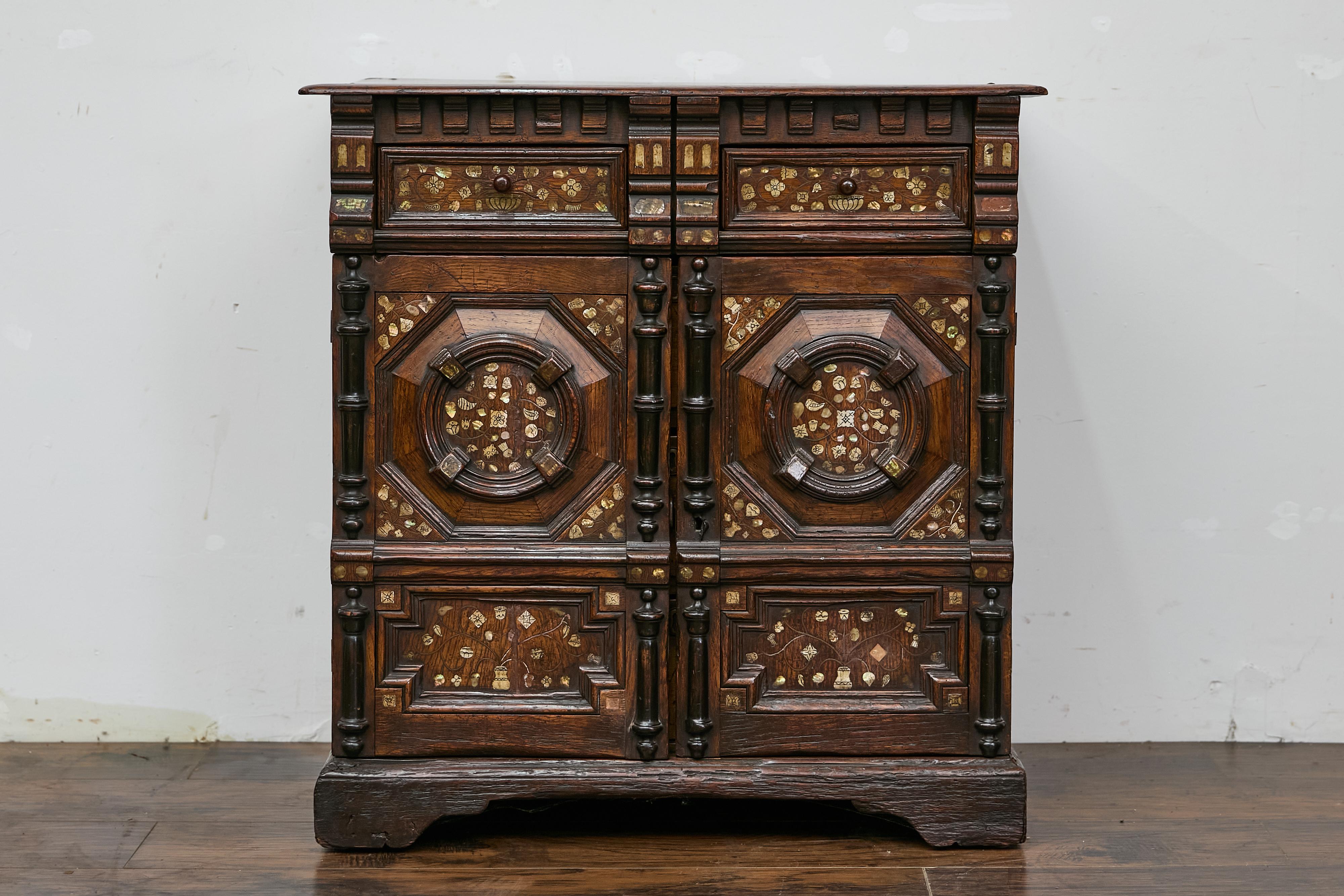 An English Renaissance Revival oak livery cupboard from the early 18th century with drawers, bone and mother of pearl inlay. This beautifully crafted livery cupboard, functioning as a storage cabinet, features a richly carved oak wood frame with