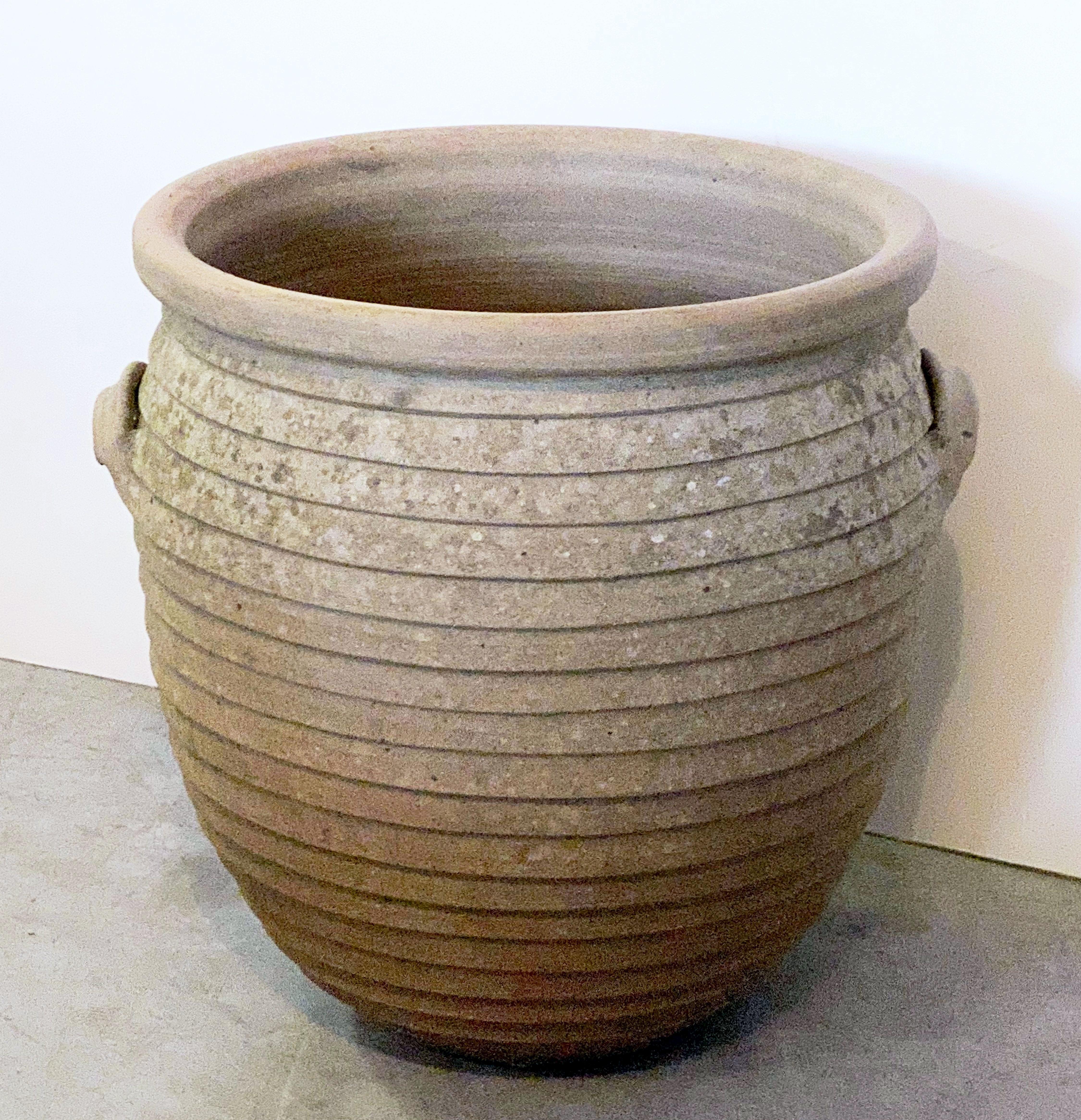 A fine English garden pot or urn of terracotta pottery, featuring a rolled edge over a ribbed design around the circumference of the planter or jar, with two handles.

Dimensions are height 17 1/2 inches x diameter 18 1/2 inches.