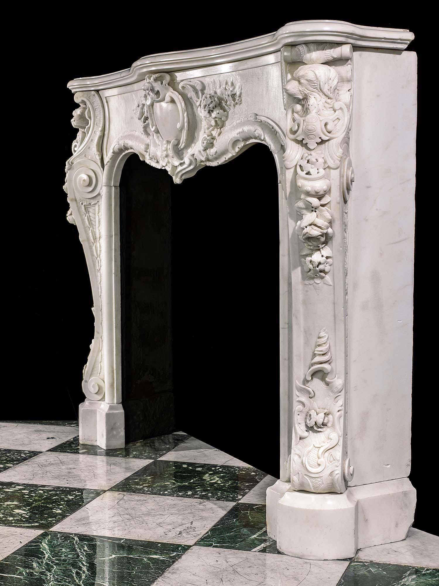 Rare et remarquable cheminée ancienne en marbre statuaire rococo anglais, à la décoration florale et rocaille richement et minutieusement sculptée. Le cartouche central, de conception et d'exécution audacieuses, est bordé de motifs floraux en subtil