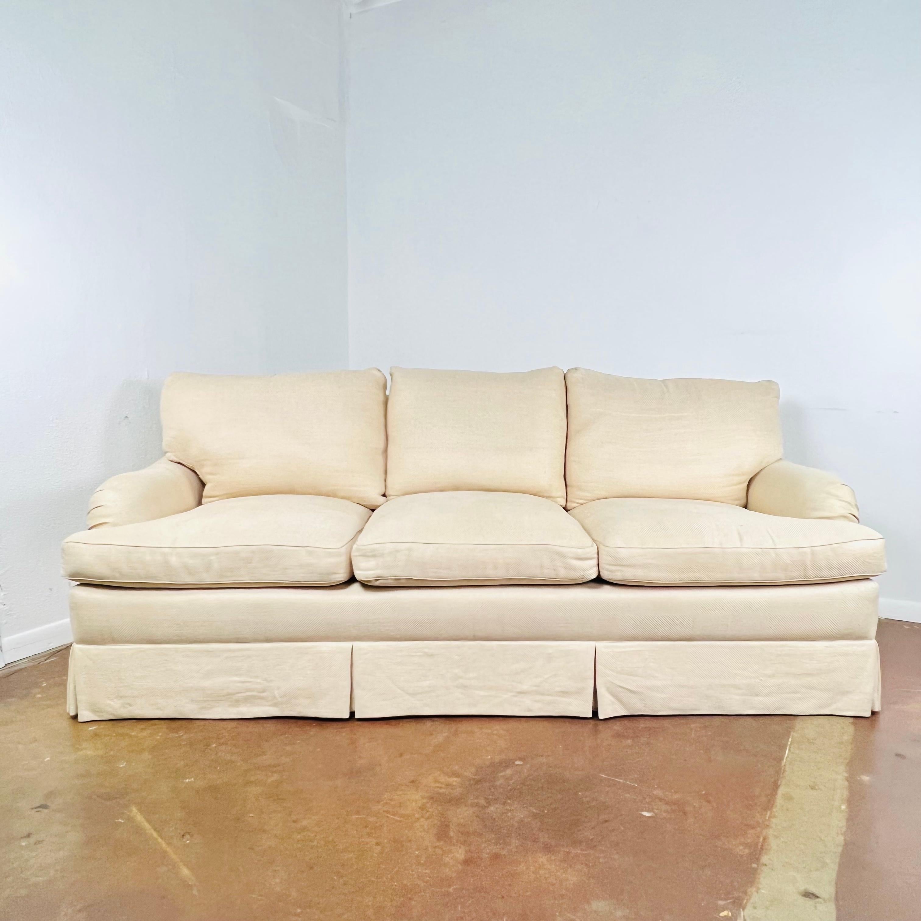 This elegant English-arm sofa features feather down wrapped T cushions, down filled loose back cushions, and tapered legs under a waterfall skirt. Reupholstery is needed due to staining and wear from age and use. Good structural condition. Ask us