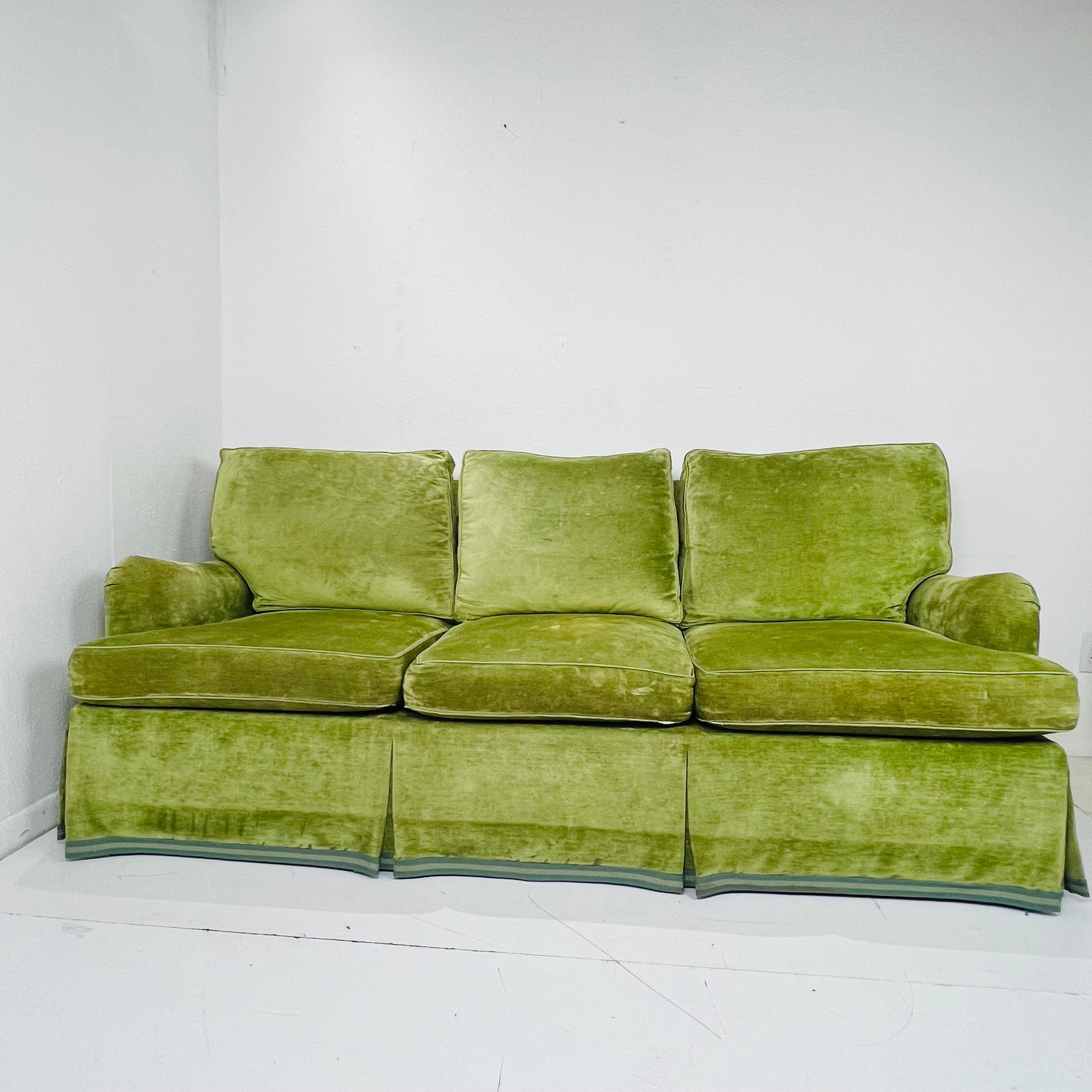 Three seat skirted rolled arm sofa.  Comfortable and in very good structural condition; previously reupholstered in Cowtan & Tout velvet, but because fabric shows staining and discoration on cushions, reupholstery is recommended. 