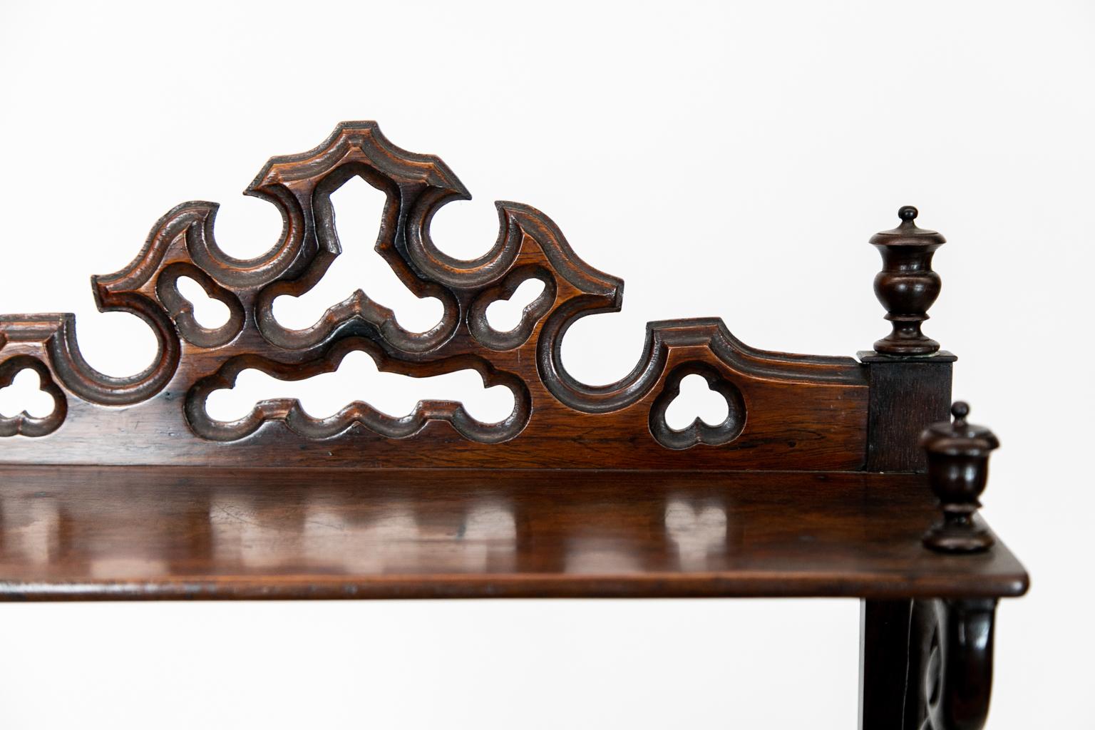 English rosewood four-tier display shelf with shaped and carved galleries on three levels. The bottom section has three divisions and the top shelf has carved scroll supports. The bottom two shelves have turned supports and turned support panels on