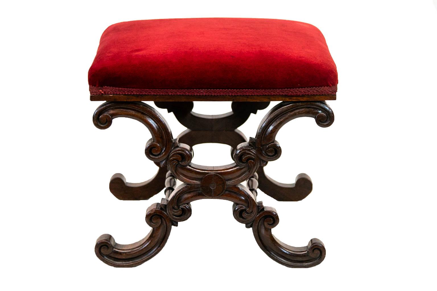 The side supports of this stool are carved with double reversed volutes which are joined by double cross stretchers. The upholstery is in good condition.