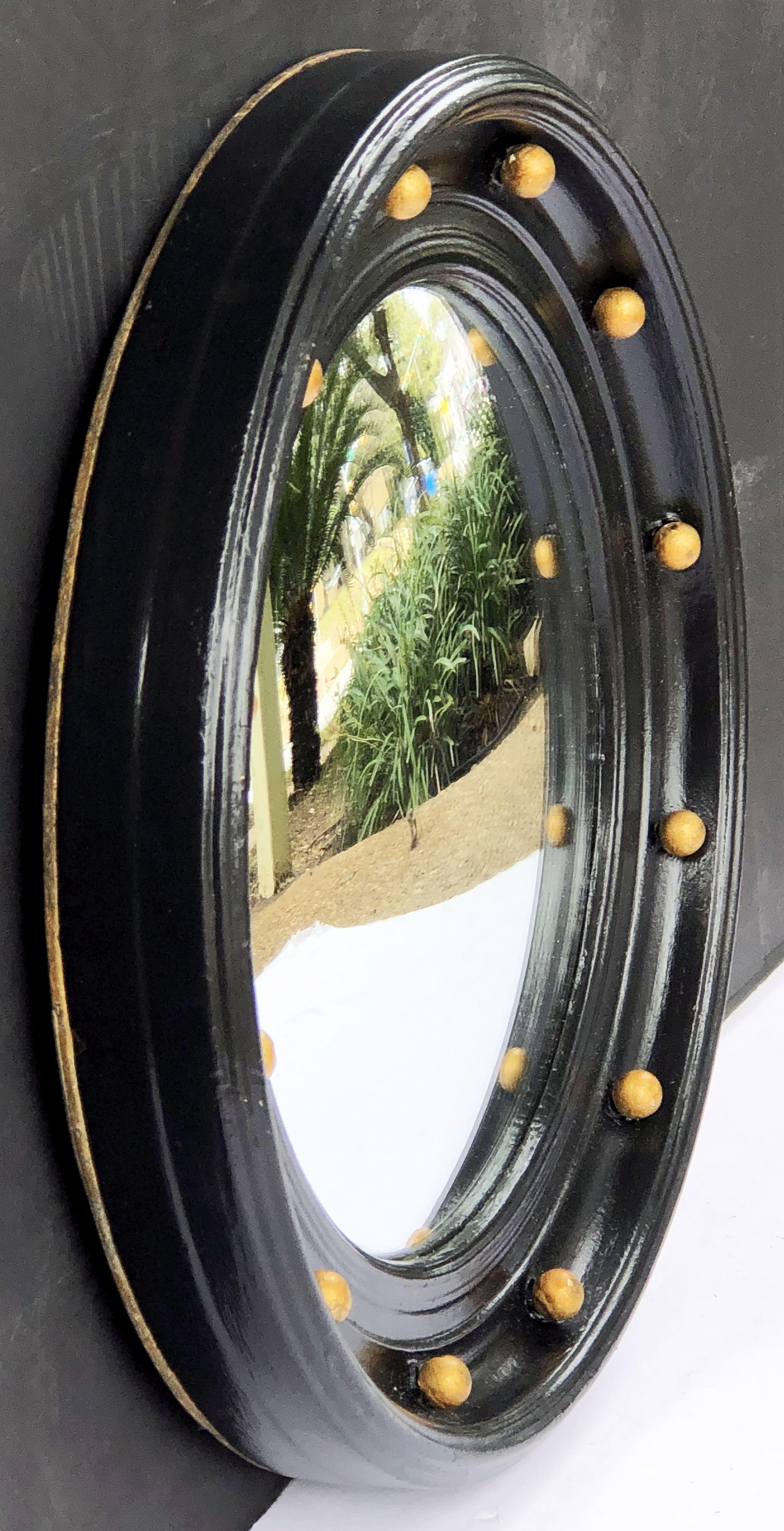 A fine English round or circular convex mirror featuring a Regency design of a molded, ebonized frame with gilt balls around the circumference.

Measures: Diameter is 14 inches.