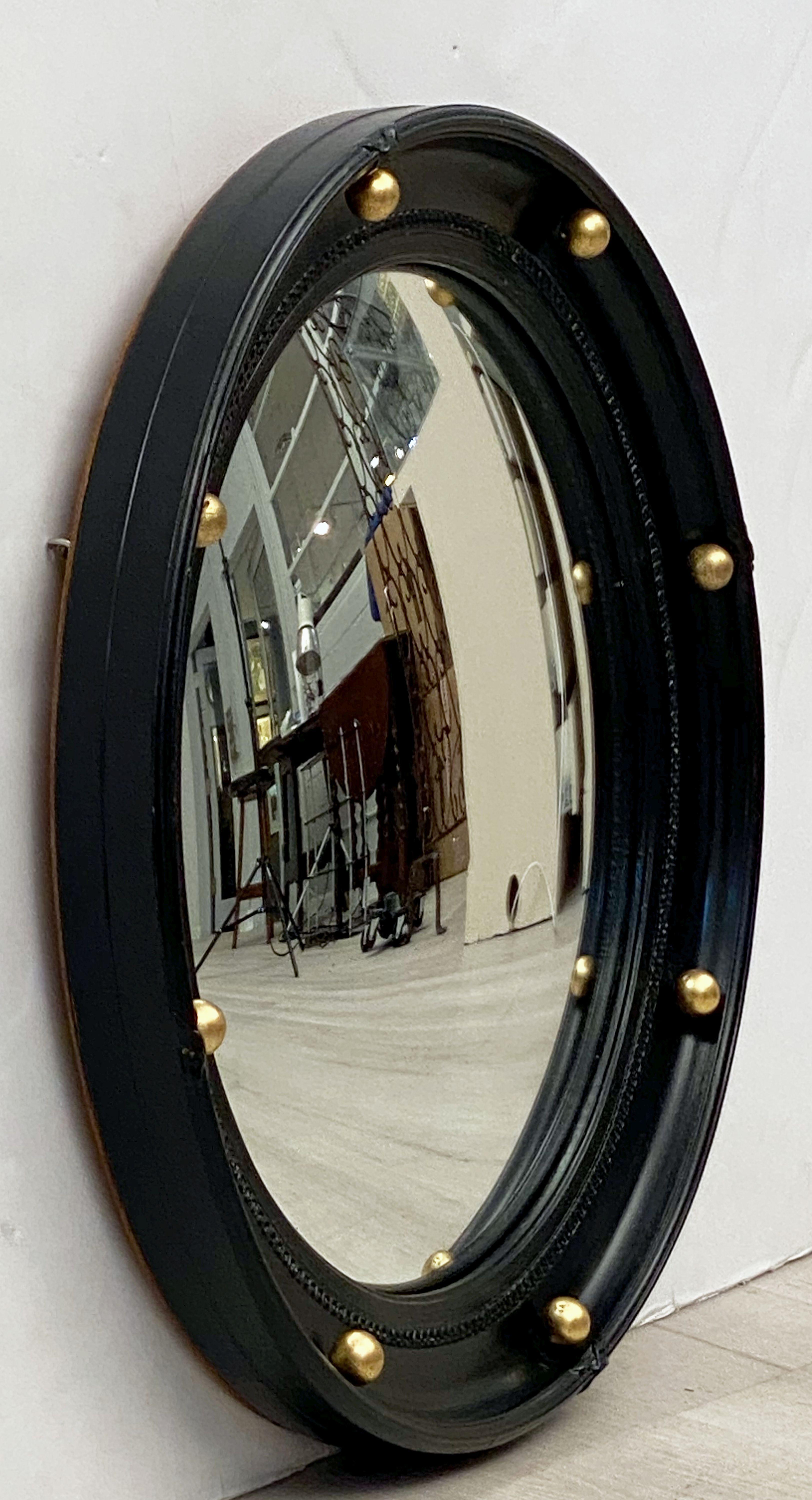 A fine English round or circular convex mirror featuring a Regency design of a molded, ebonized frame with gilt balls around the circumference.

Measures: Diameter is 17 3/8 inches.