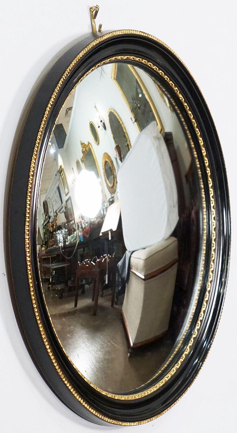 A fine English round or circular convex mirror featuring a Regency style design of a molded, ebonized frame with gilt accents around the circumference.

Measures: Diameter is 18 1/2 inches